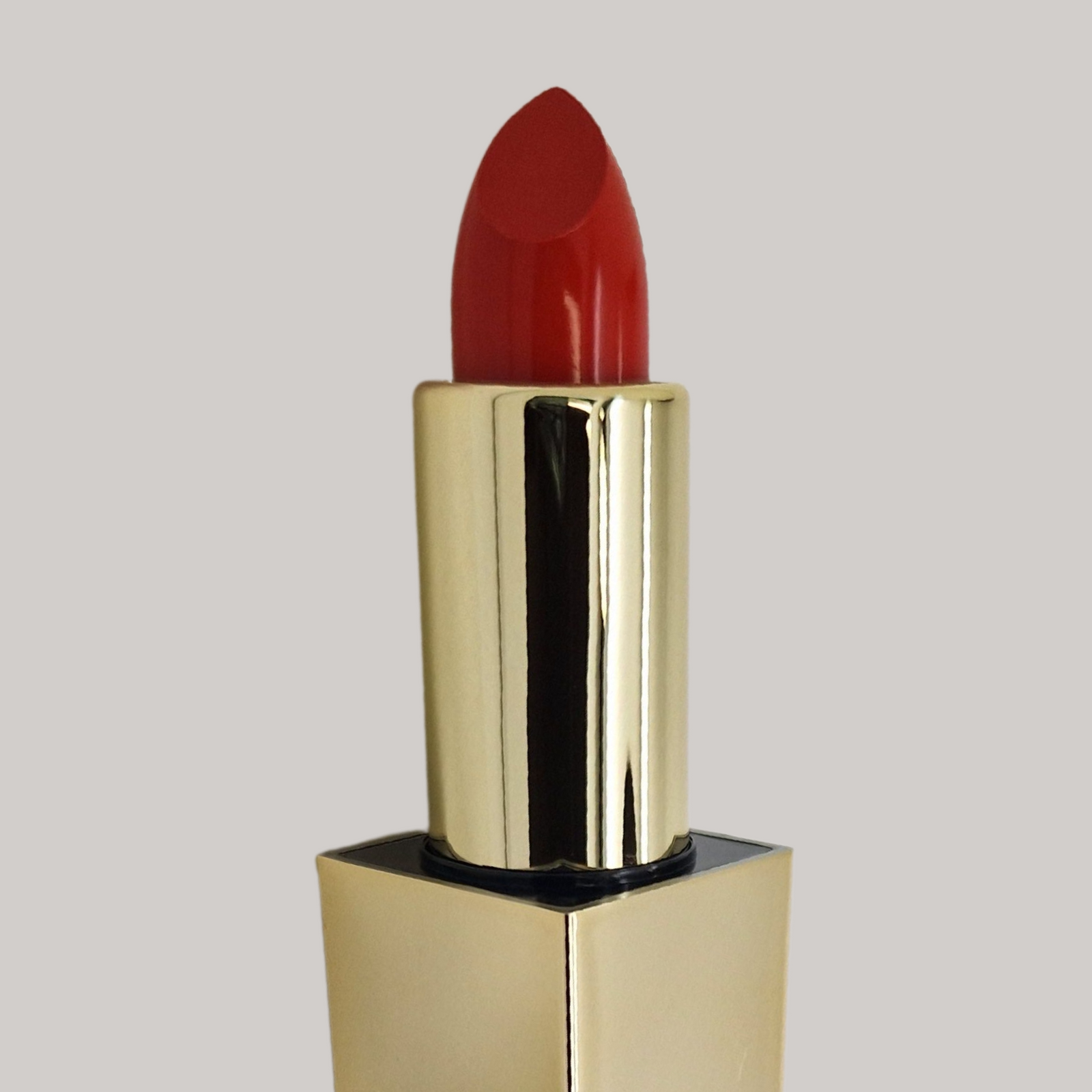close up image of red lipstick in a golden applicator