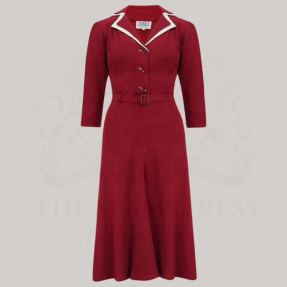A red, knee-length shirtwaister dress with contrasting cream undercollar and square jet-style buttons