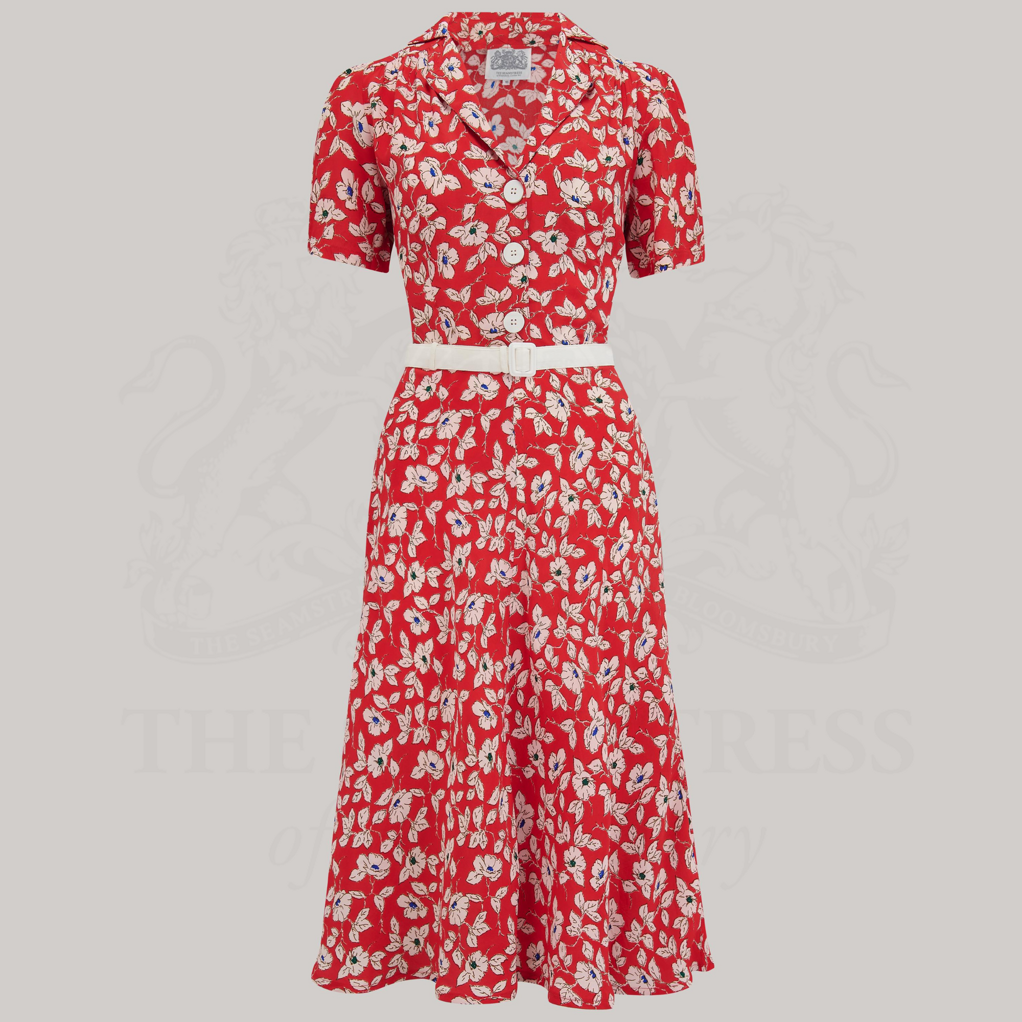 A classic 1940s shirtwaist dress in a red floral pattern. The dress has short sleeves, a revere collar, and a contrasting cream waist belt