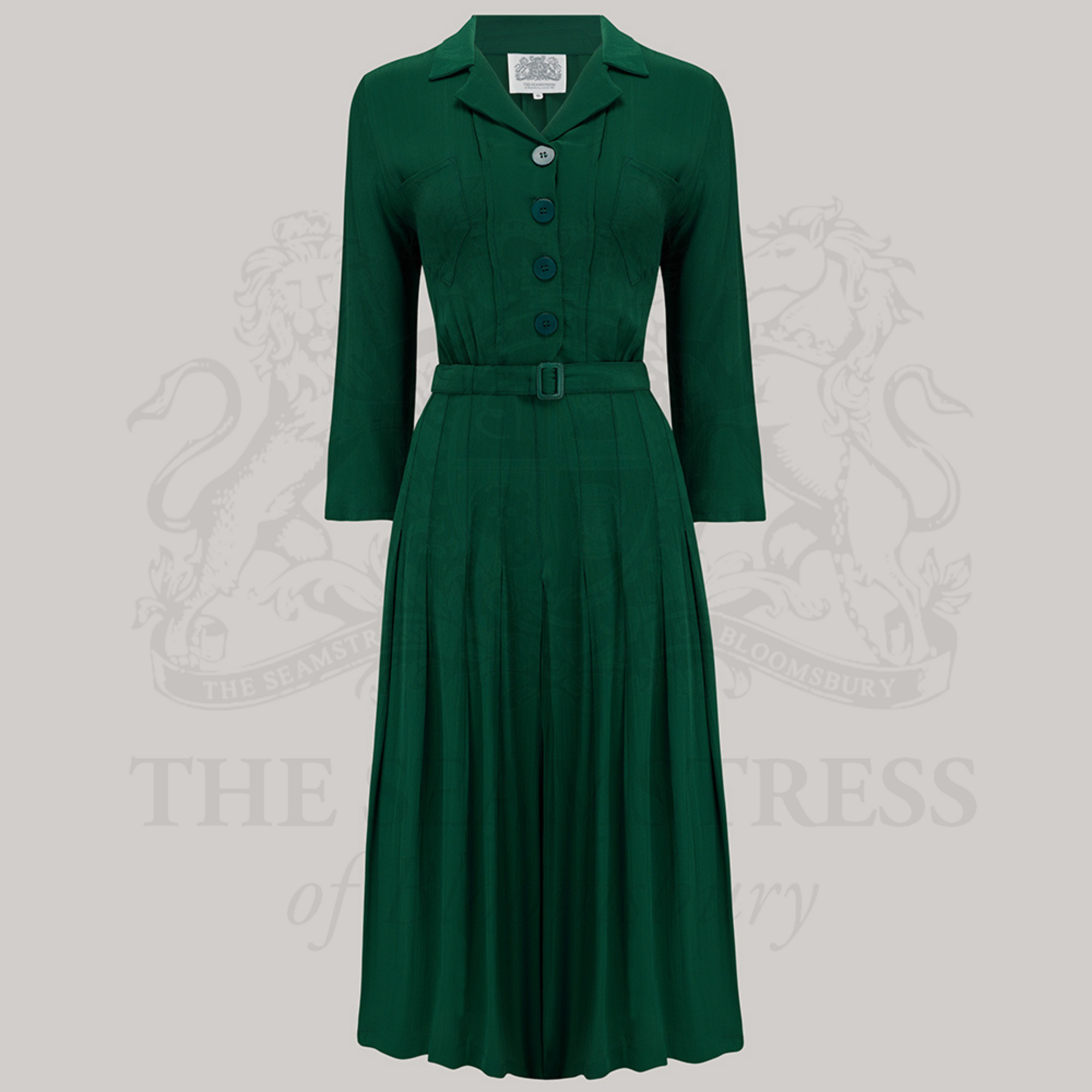 A green shirtwaist dress with bakelite-style buttons, front chest pockets, and 3/4 length sleeves. 