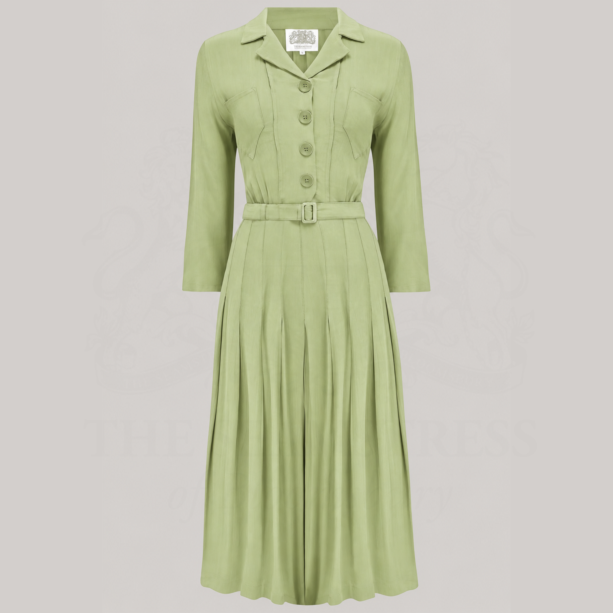 A light pistachio green long-sleeve midi dress with a collar, button-up front, and matching belt, shown against a solid light grey background.