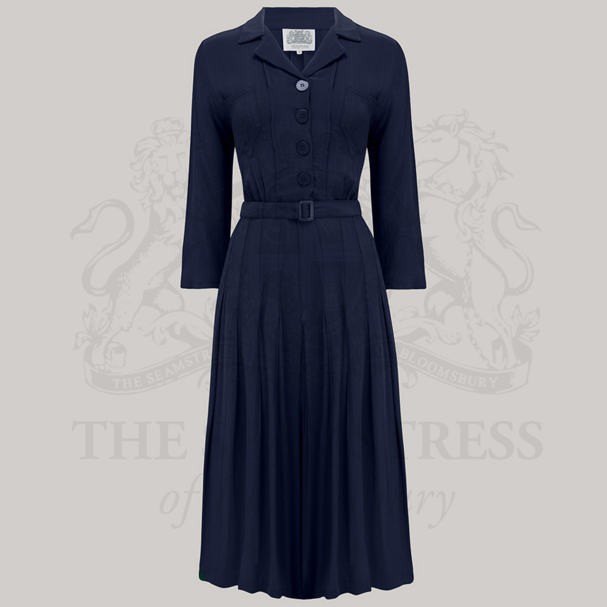 A navy shirtwaist dress with bakelite-style buttons, front chest pockets, and 3/4 length sleeves. The dress features a pin-stitched skirt.