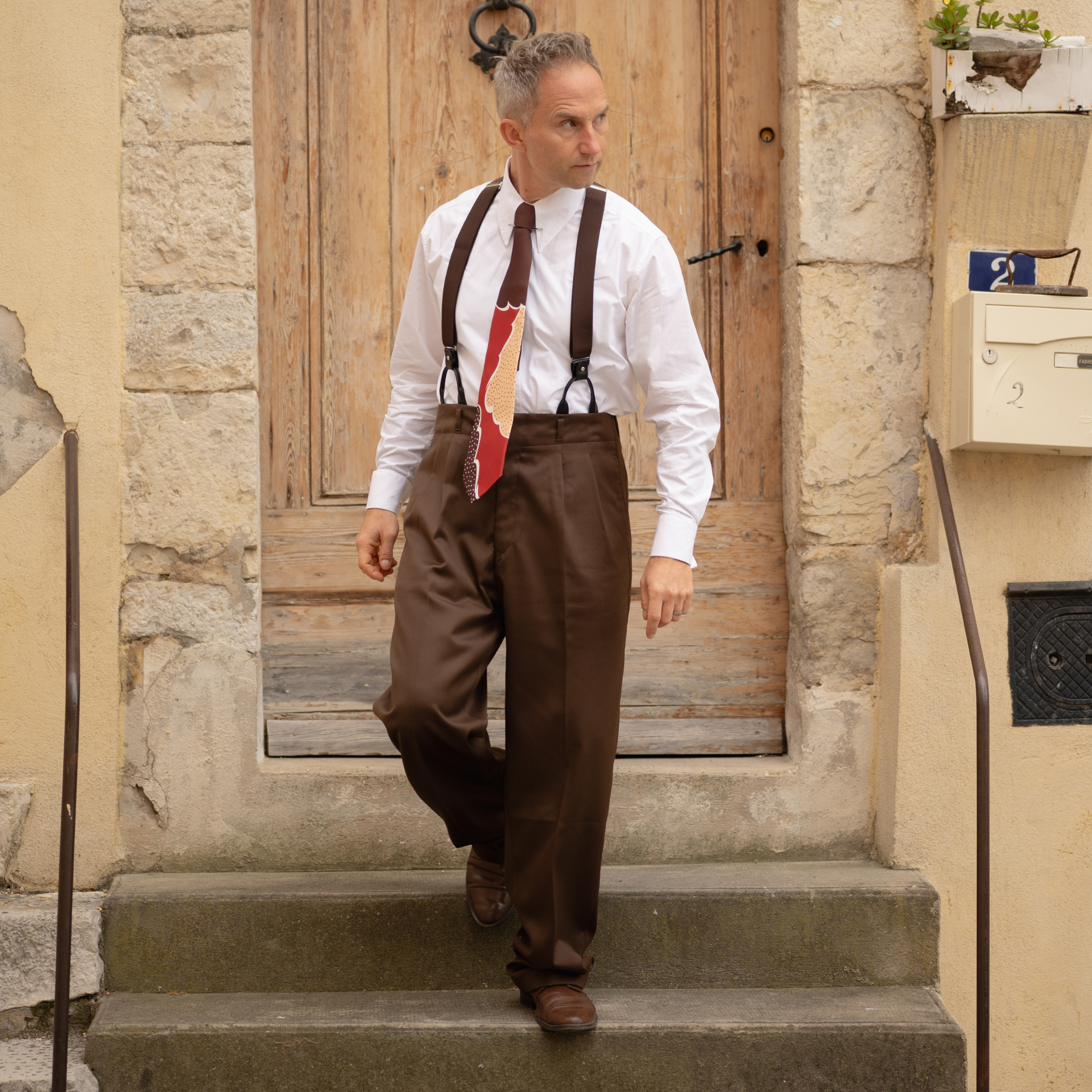 Man in vintage attire standing on stone steps outside a building.
