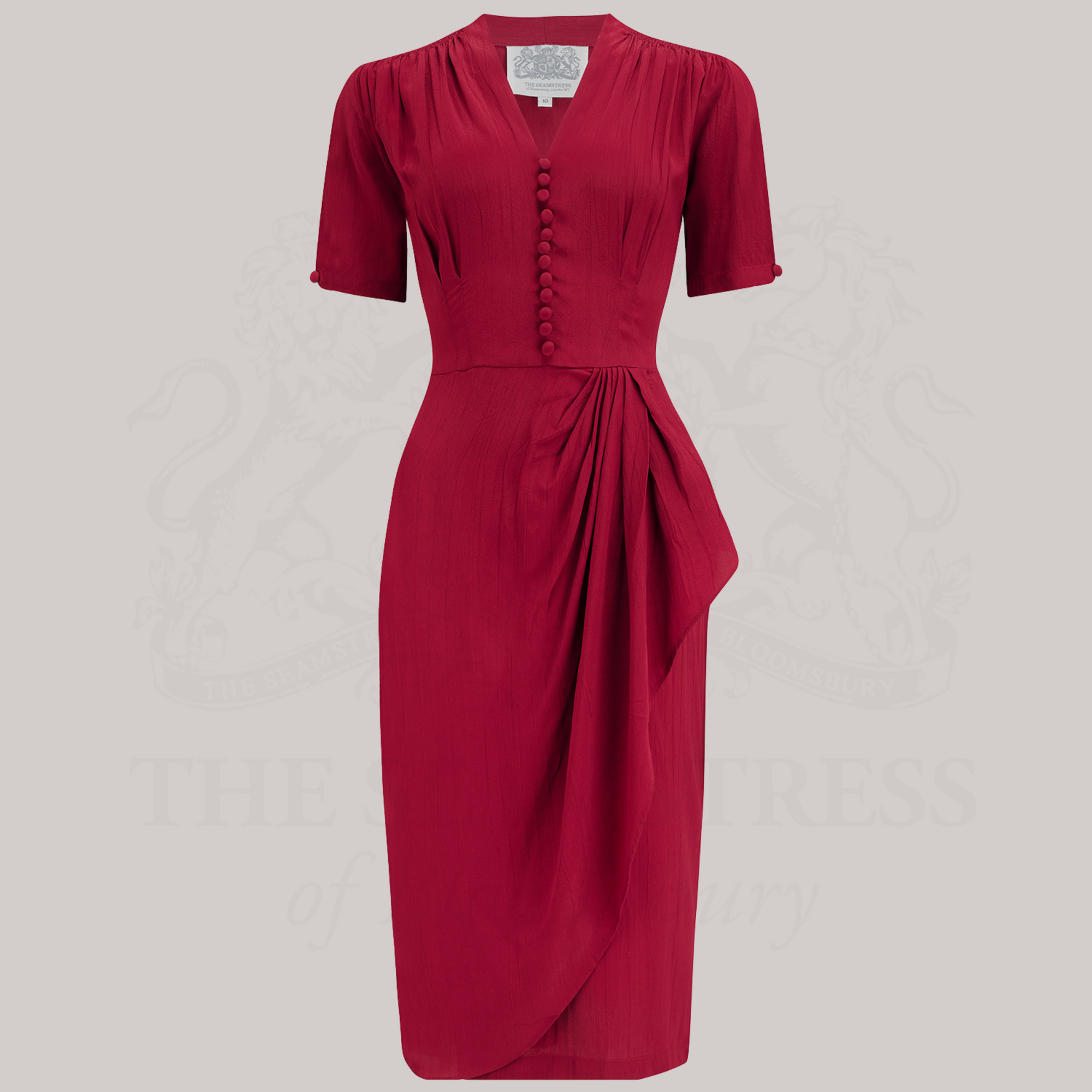 A red, short-sleeved dress with a fitted style, featuring a waterfall ruffle on the waist, decorative buttons on the front bodice, and side seam pockets.