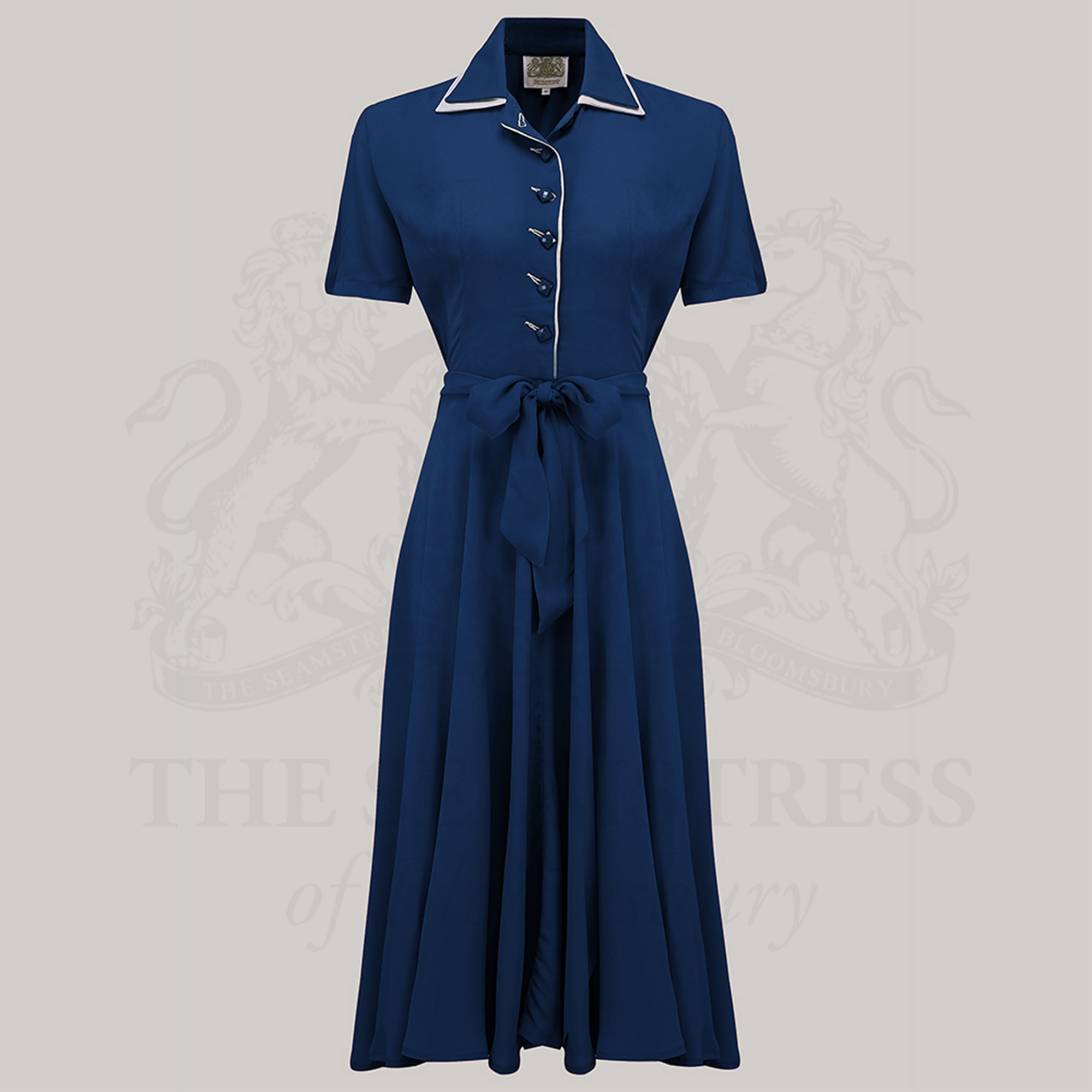 A navy blue tea dress with square jet-style buttons and a cream undercollar.
