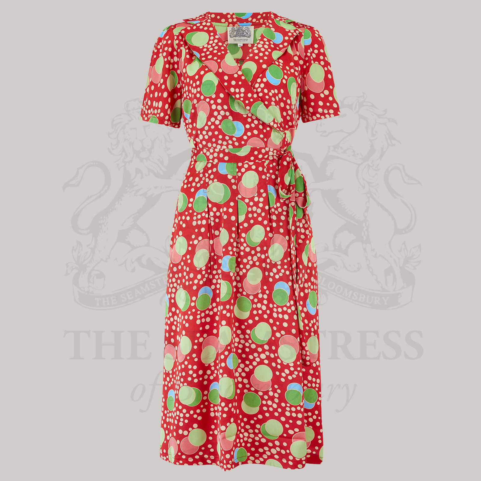 A red wrap dress with a tie around the waist and a pattern of colorful dots.