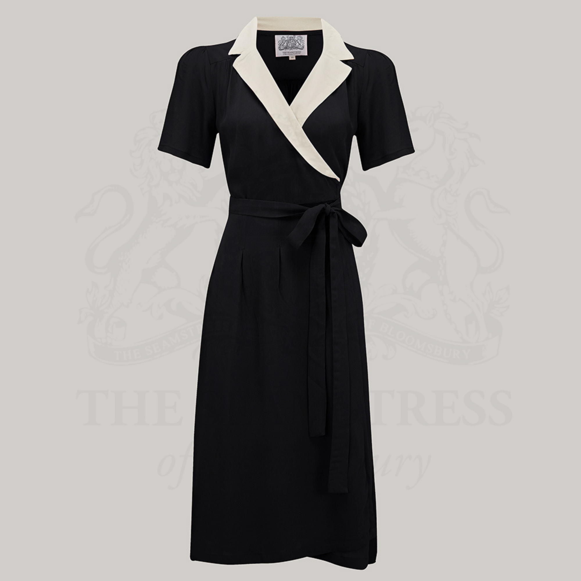 A black and ivory Peggy Wrap Dress with a V-neck, tie at the waist, box pleats at the waistband, and side-seam pockets.