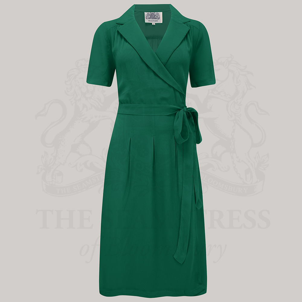A green, short-sleeved Peggy wrap dress with a tie at the waist and box pleats at the waistband