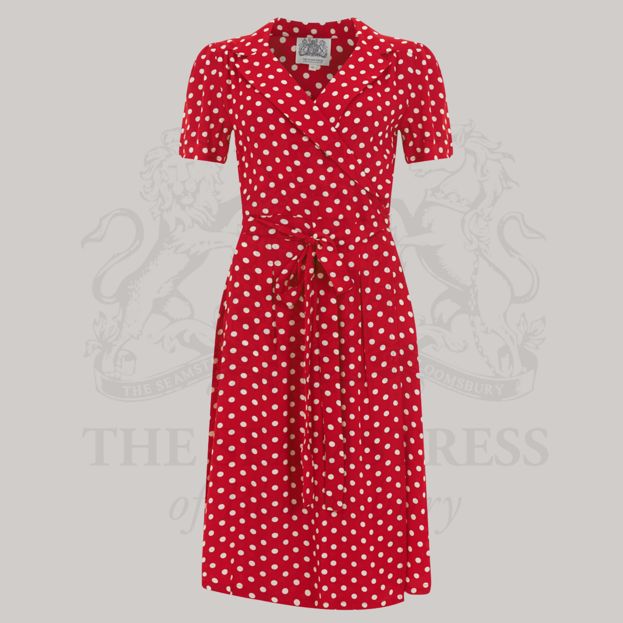 A red and white polka dot dress with a v-neck and tie at the waist, made from crepe de chine fabric.