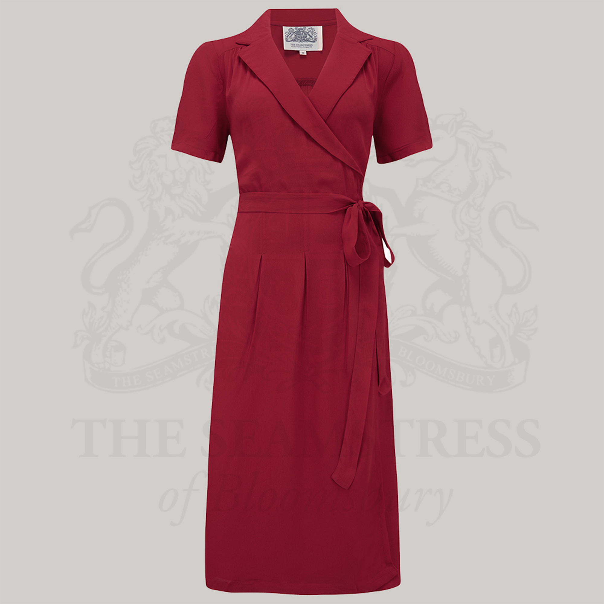 A red, short-sleeved Peggy wrap dress with a tie at the waist and V-neck, made from Crepe de Chine fabric.