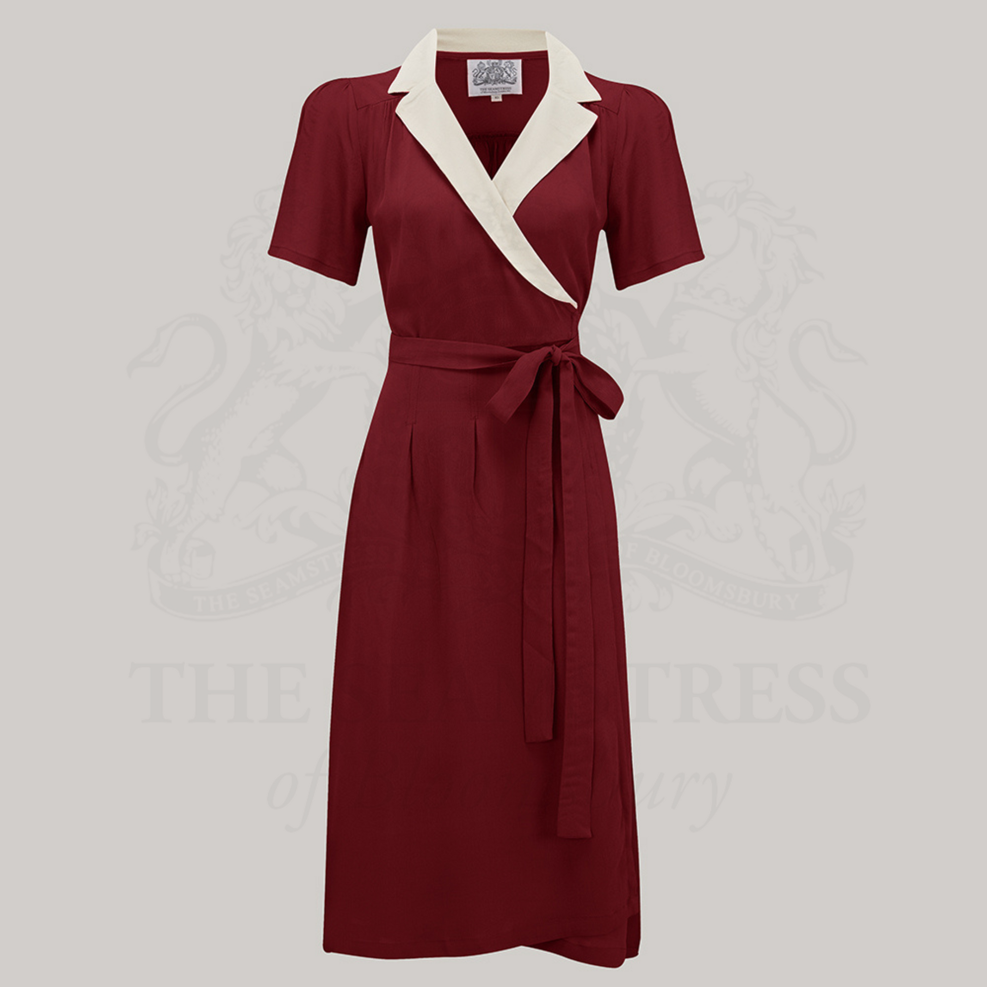 A red and ivory vintage-style wrap dress with a tie at the waist, V-neck, and short sleeves.