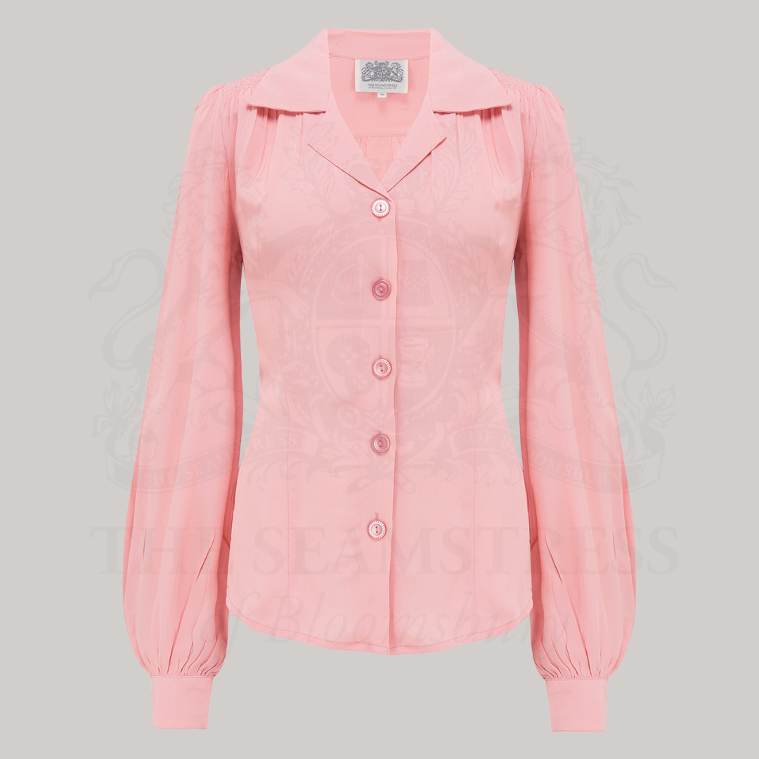 A vintage style blouse in blossom pink with a revere collar, long sleeves with full cuffs, and a fitted waist.