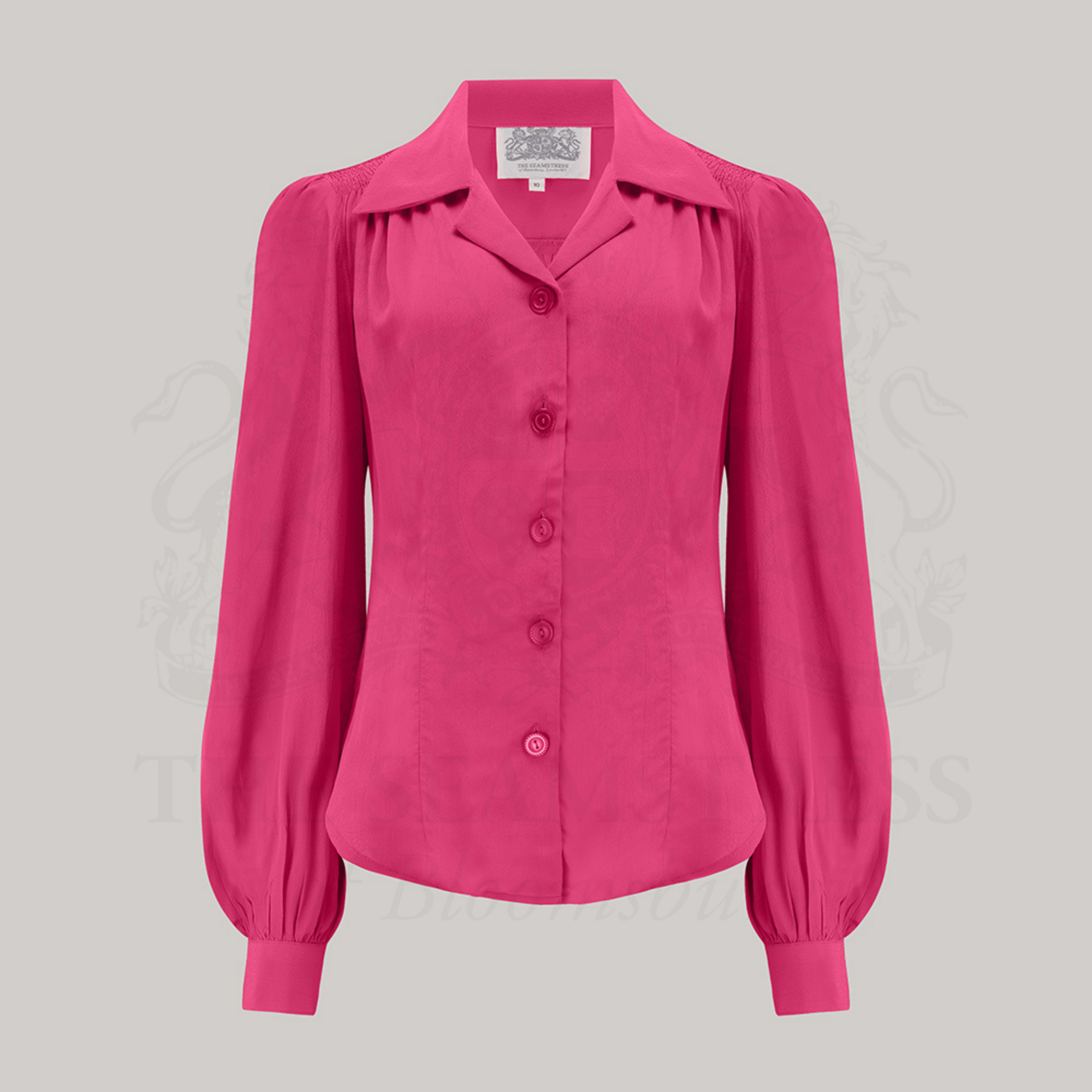 A raspberry blouse with a revere collar, long bishop sleeves with full cuffs, and a fitted waist. The blouse features shoulder pads and is made from Crepe de Chine fabric.