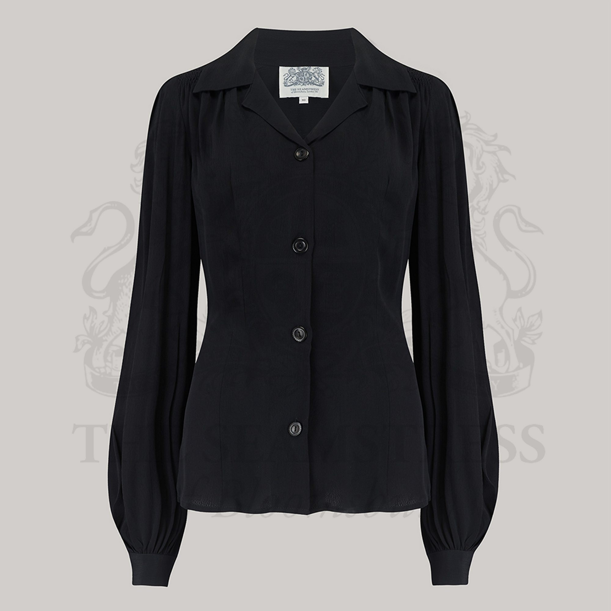 A black, long-sleeved blouse with a revere collar and fitted waist, made from crepe de chine fabric.
