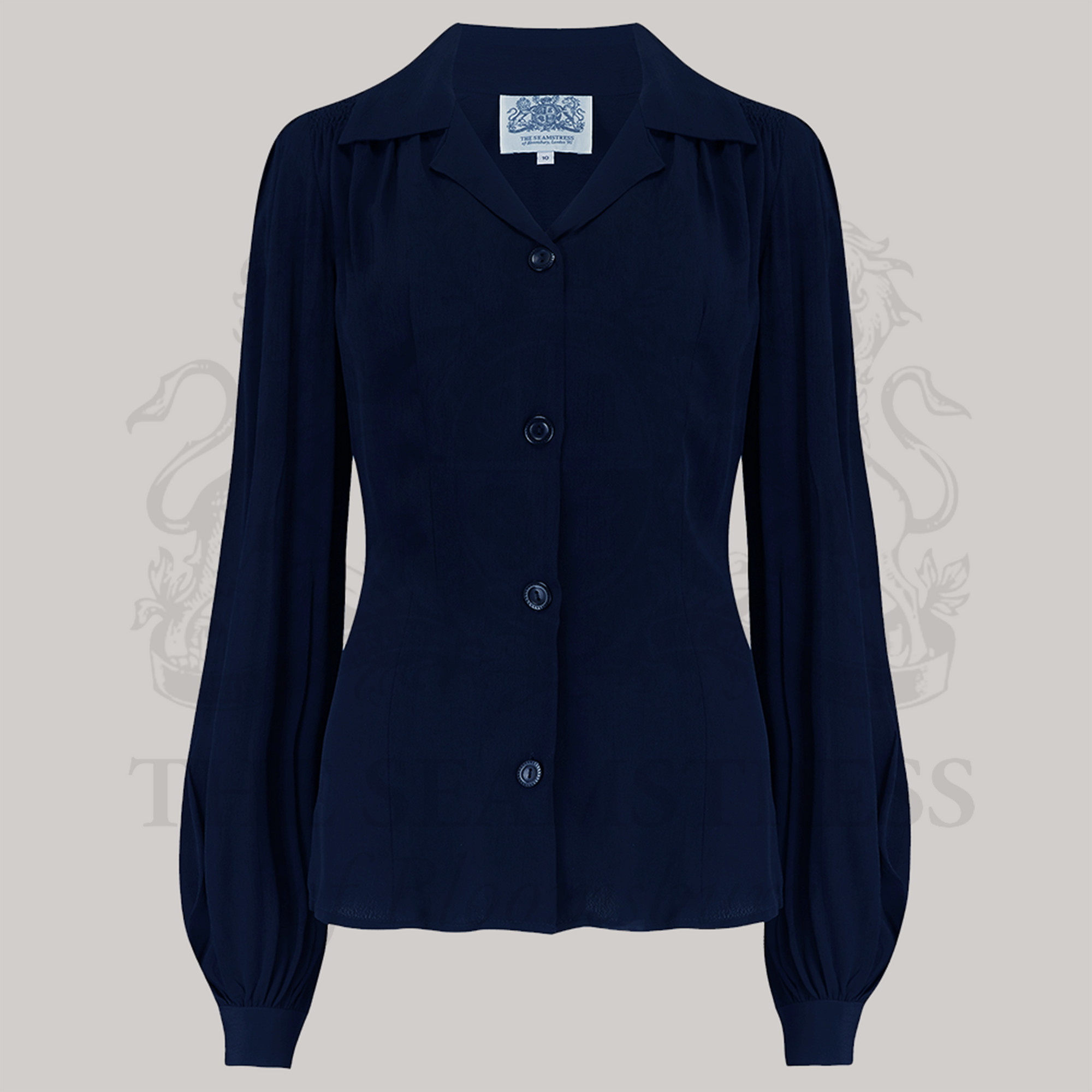 A navy-colored blouse with a revere collar, long bishop sleeves with full cuffs, and a fitted waist. It features shoulder smocking detail and shoulder pads.