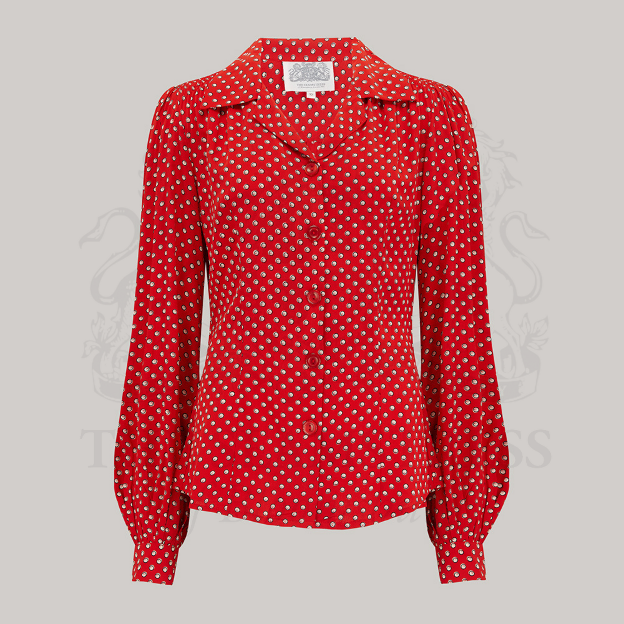 A red blouse with a polka dot pattern, featuring a revere collar and long sleeves with full cuffs