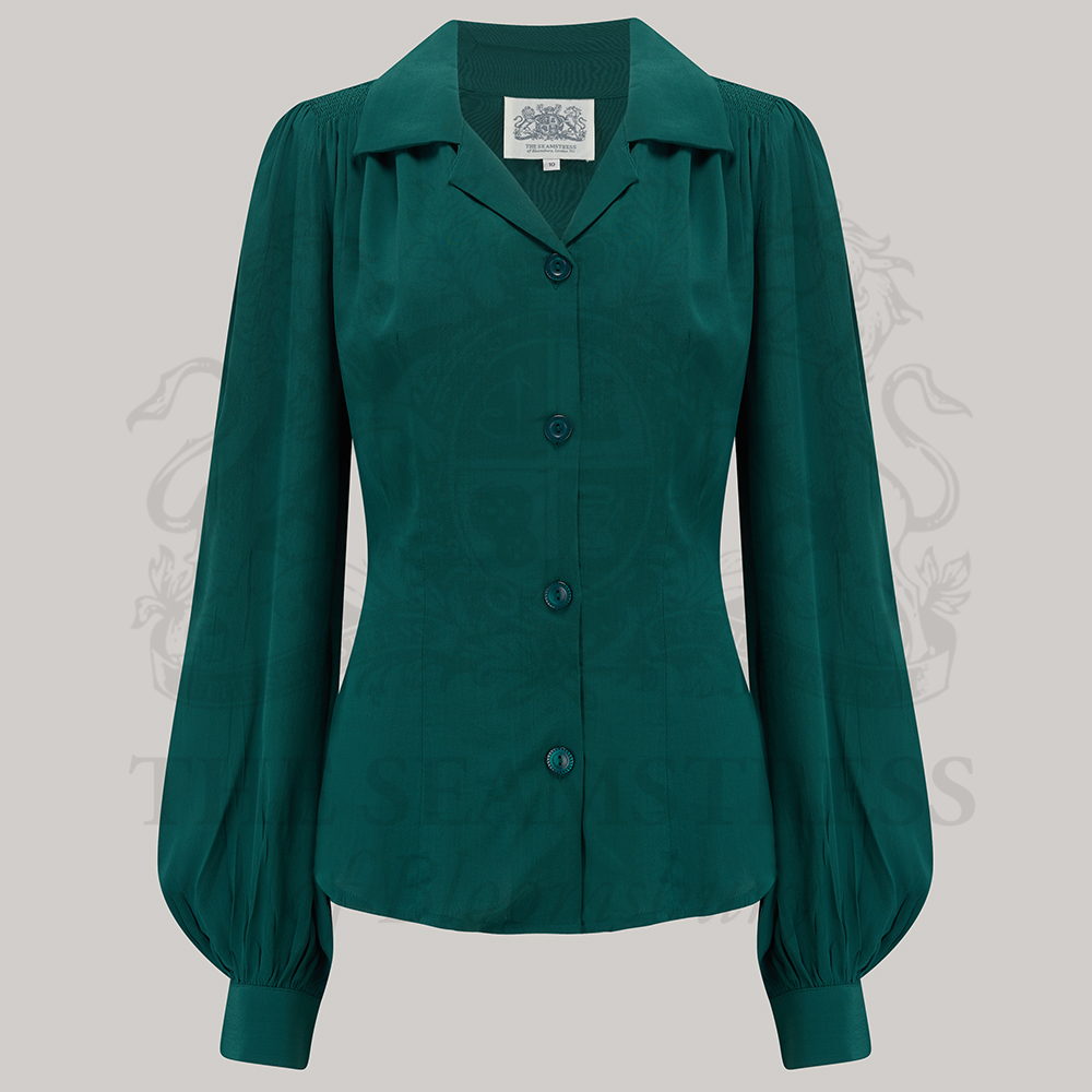 A green blouse with a revere collar, long sleeves with full cuffs, and shoulder pads. 