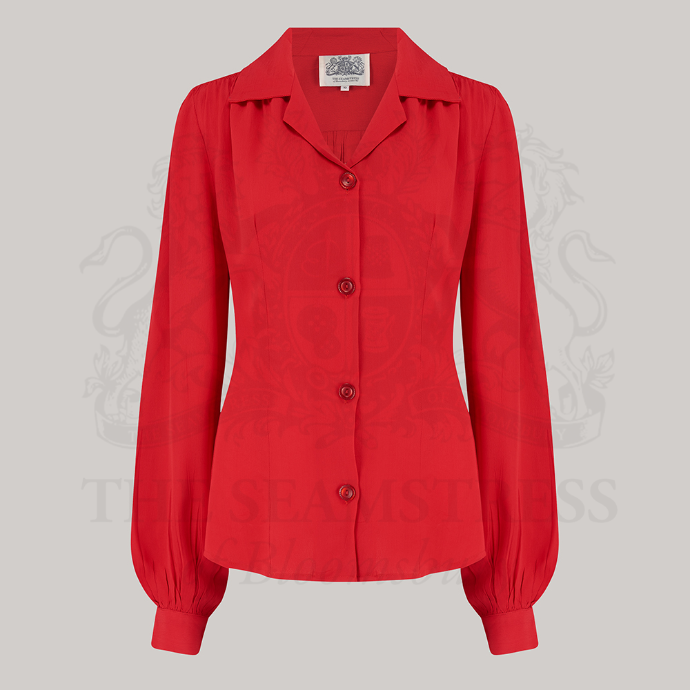 A red blouse with a revere collar, long sleeves with full cuffs, and shoulder pads.