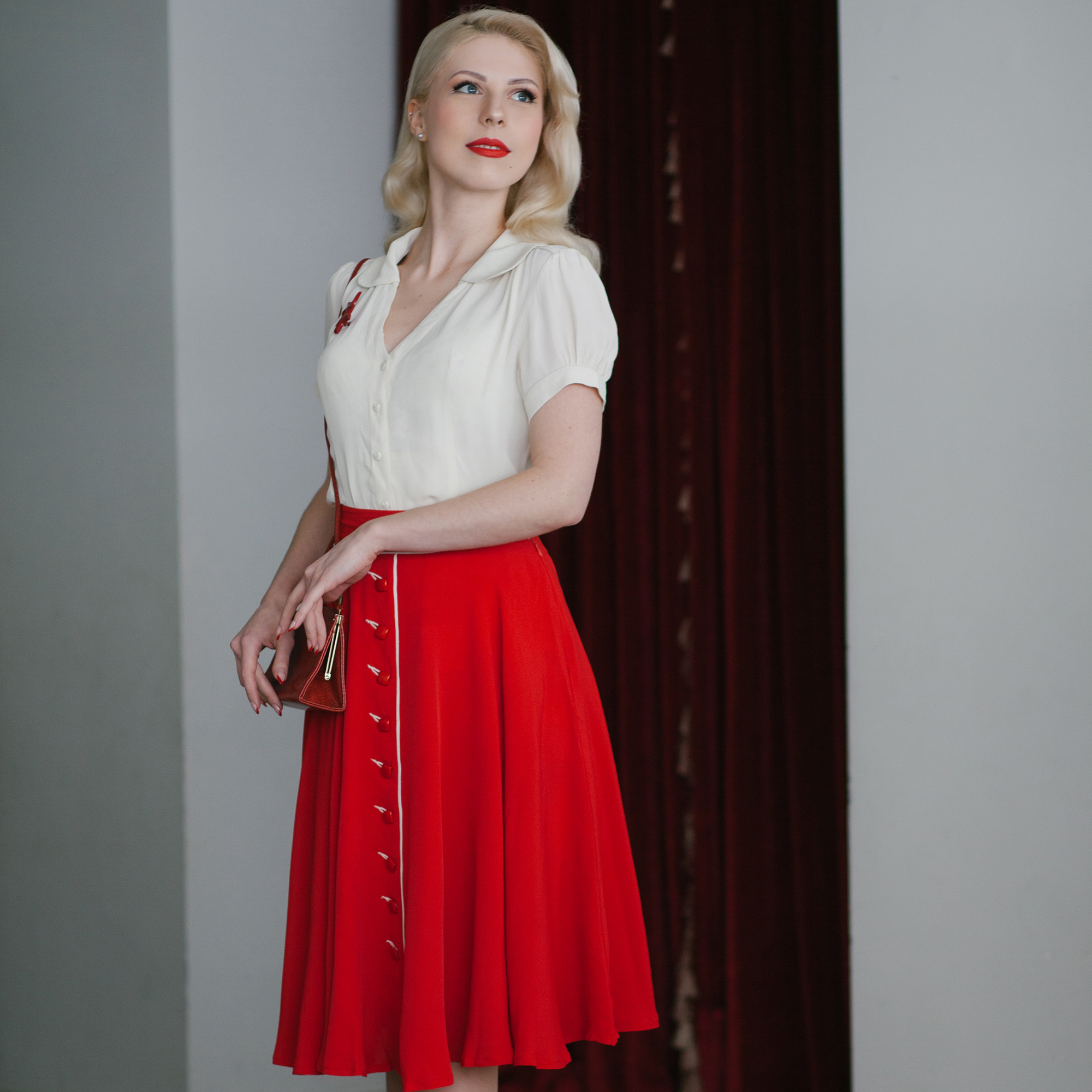 A woman wearing a red vintage dancing skirt, paired with a cream blouse and matching red accessories.