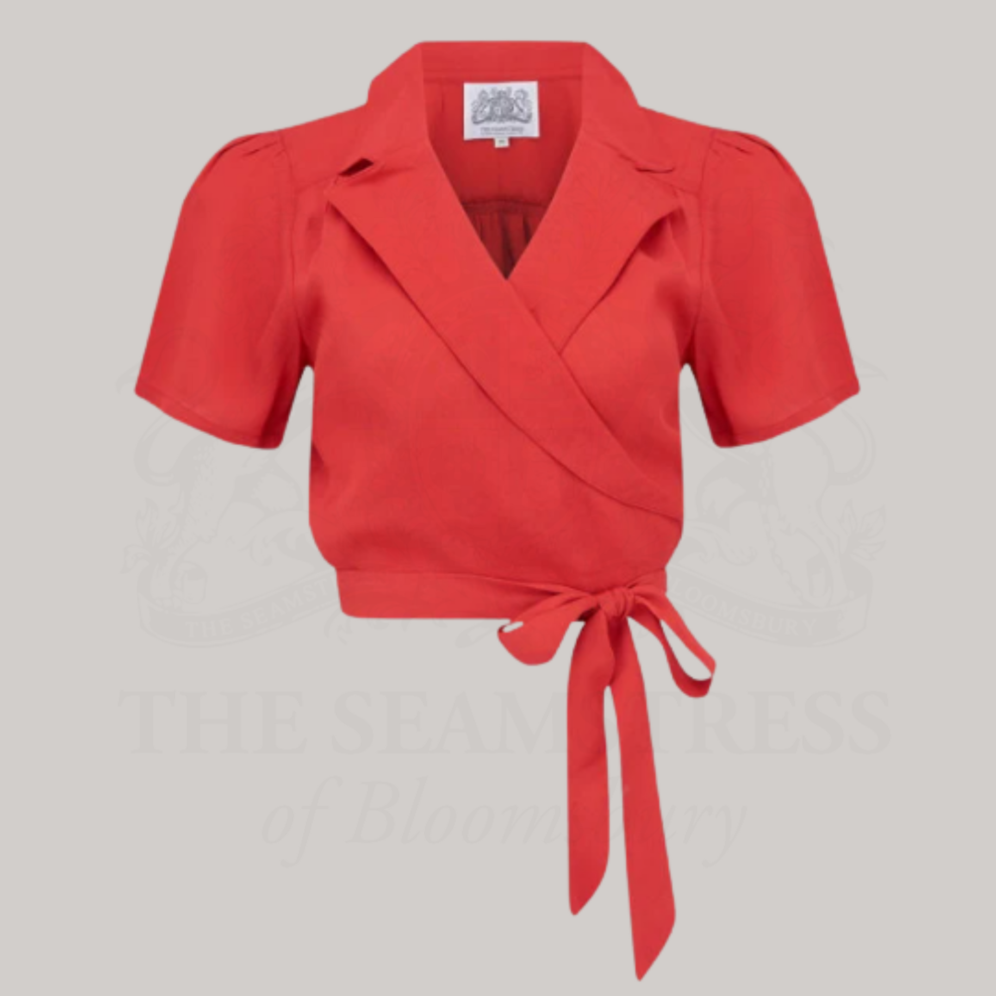 A red, short-sleeved, wrap-style blouse with a revere collar and tie waist.