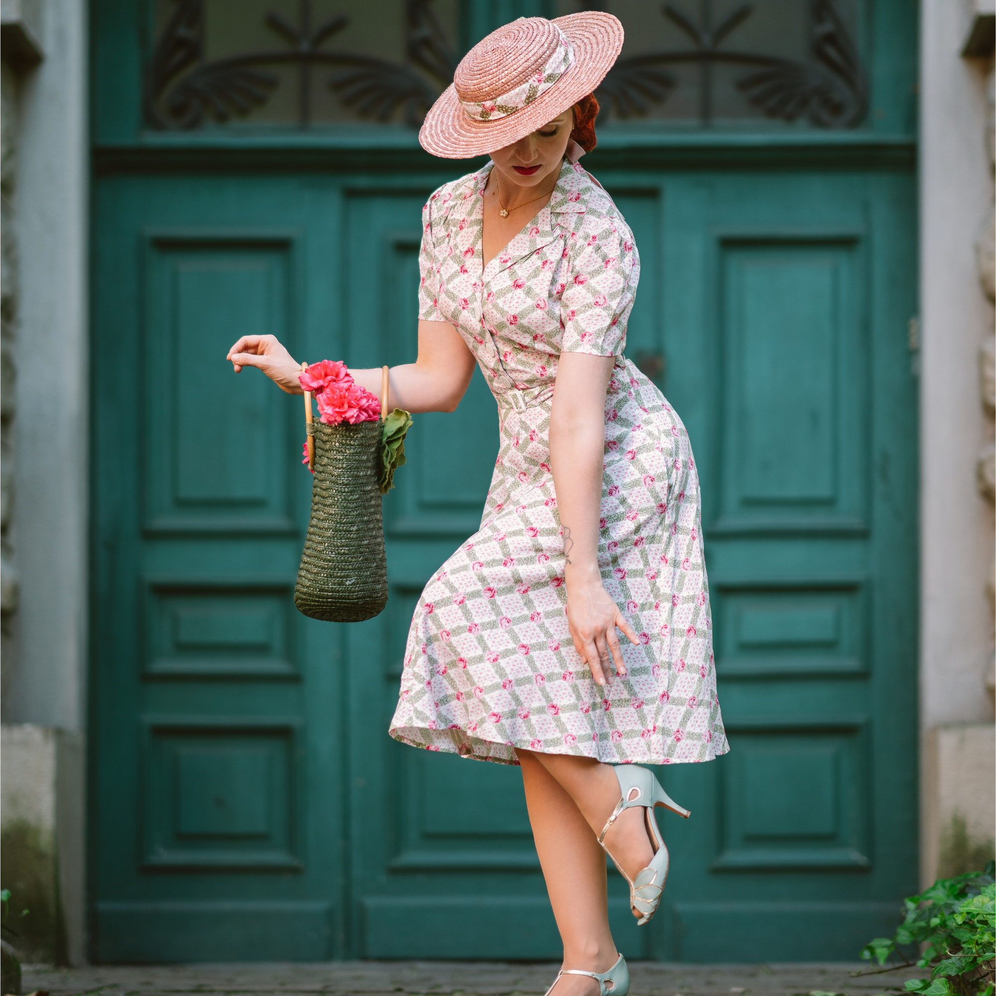 Model wears a 1940s-style shirtwaist dress in cream floral pattern. Model also wears wide brim hat with matching accessories.