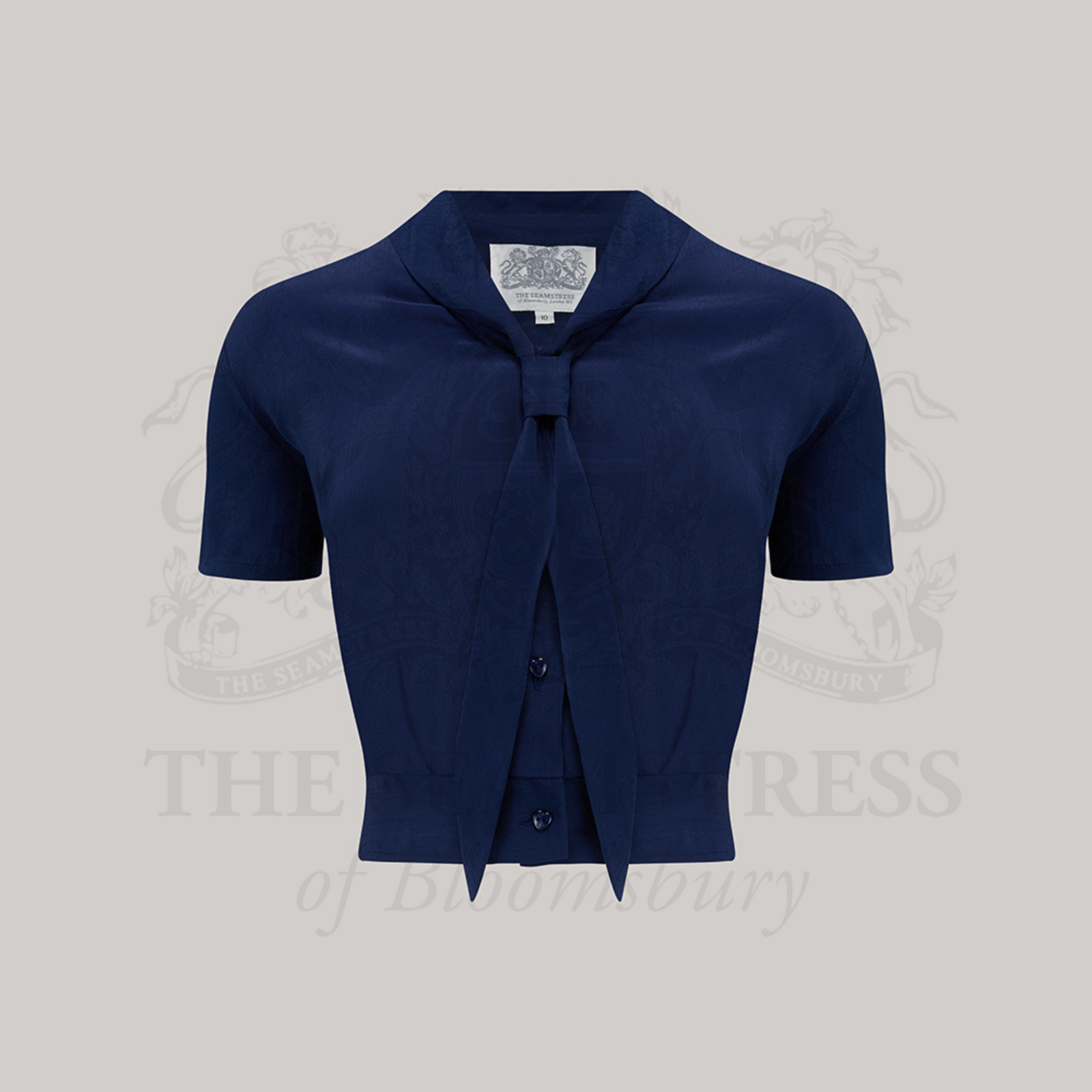 A 1940s sailor-style blouse in navy blue. Featuring a roll-style sailor collar. Small buttons run down the front of the blouse for fastening but are hidden by the long collar.
