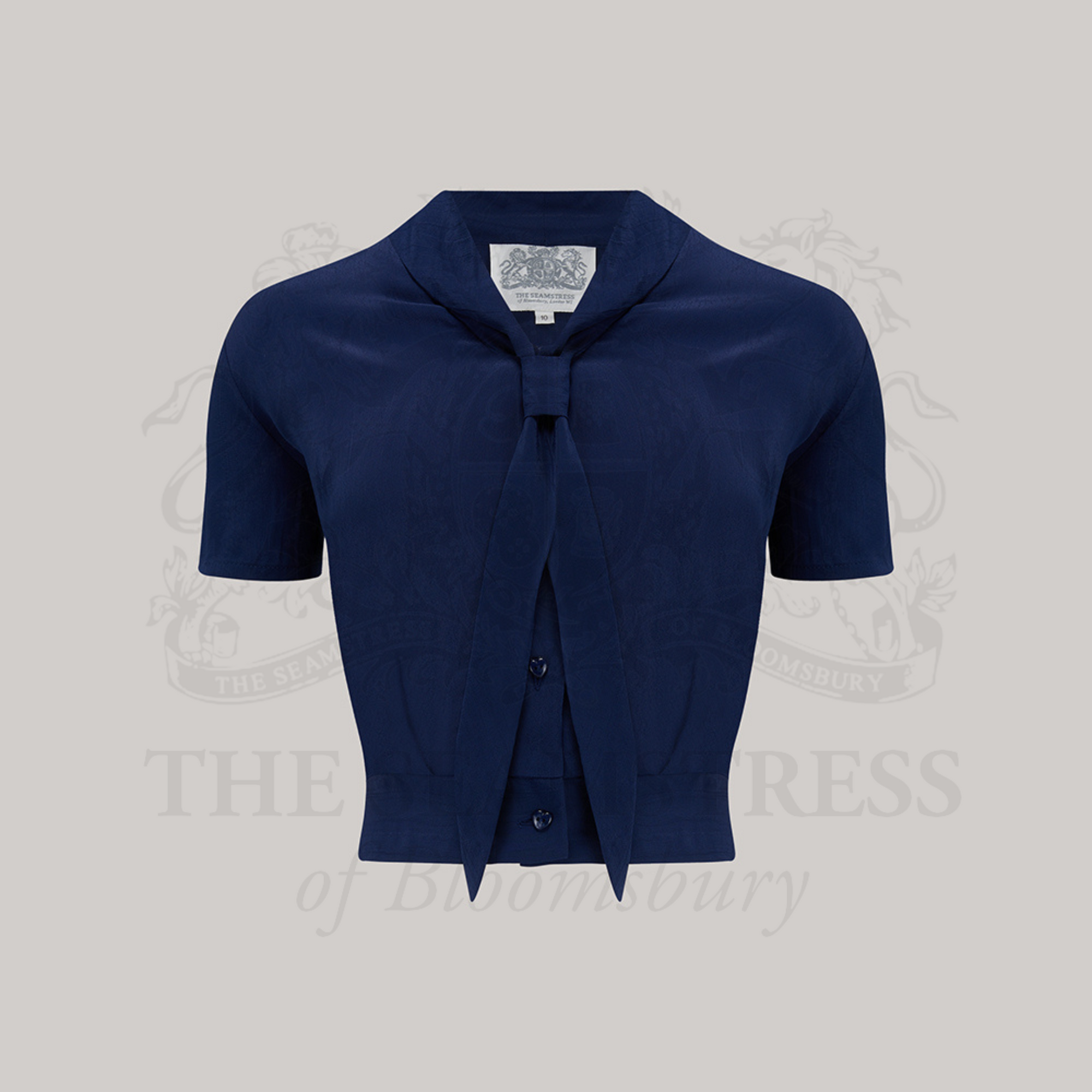 A 1940s sailor style blouse with short sleeves in navy. Featuring a roll style collar to give the iconic sailor look. Small buttons run down the front of the blouse for fastening but are hidden by the long collar.