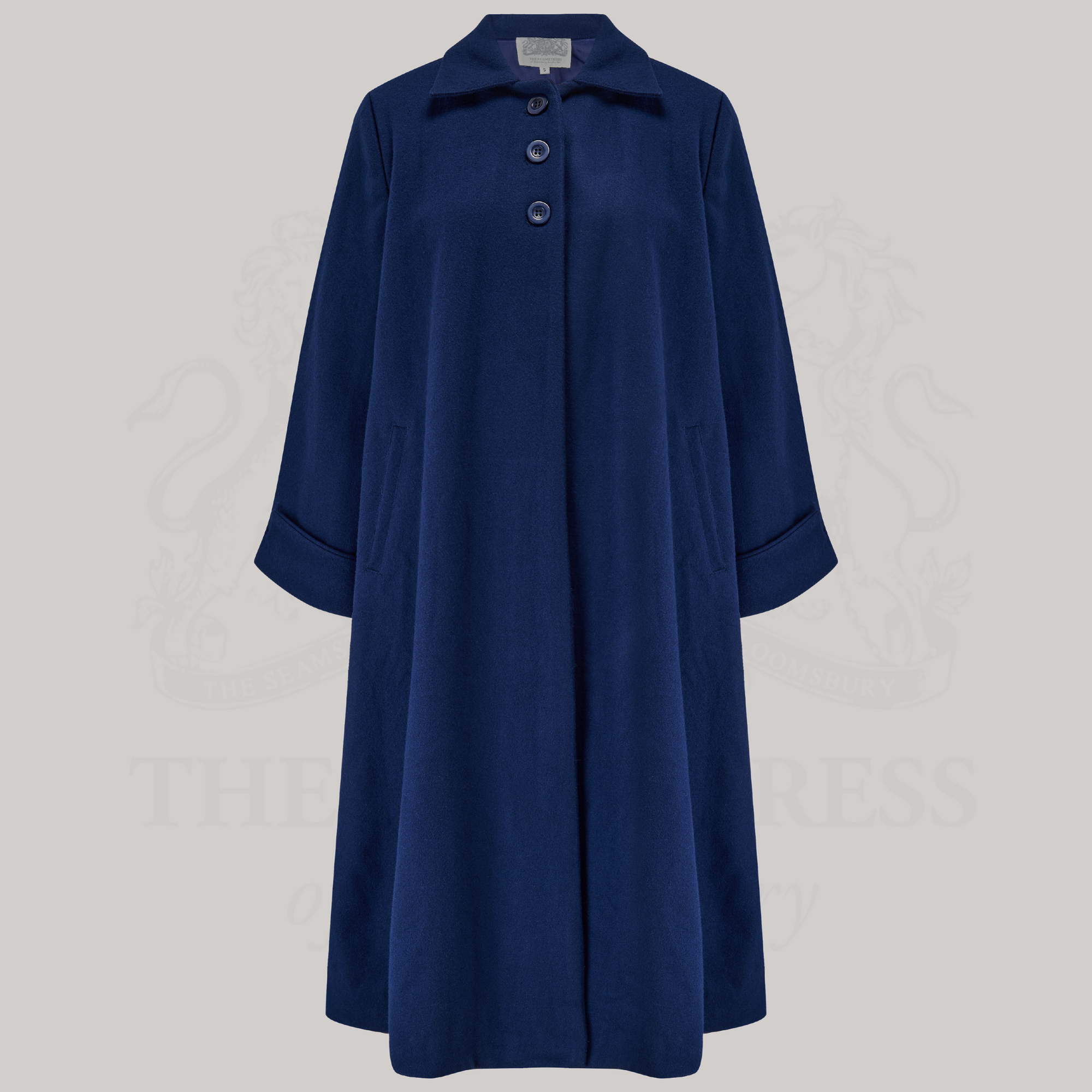A 1940s style 43 inch long swing coat in navy. It has three buttons at the top front, small shoulder pads, and is lined in satin. 