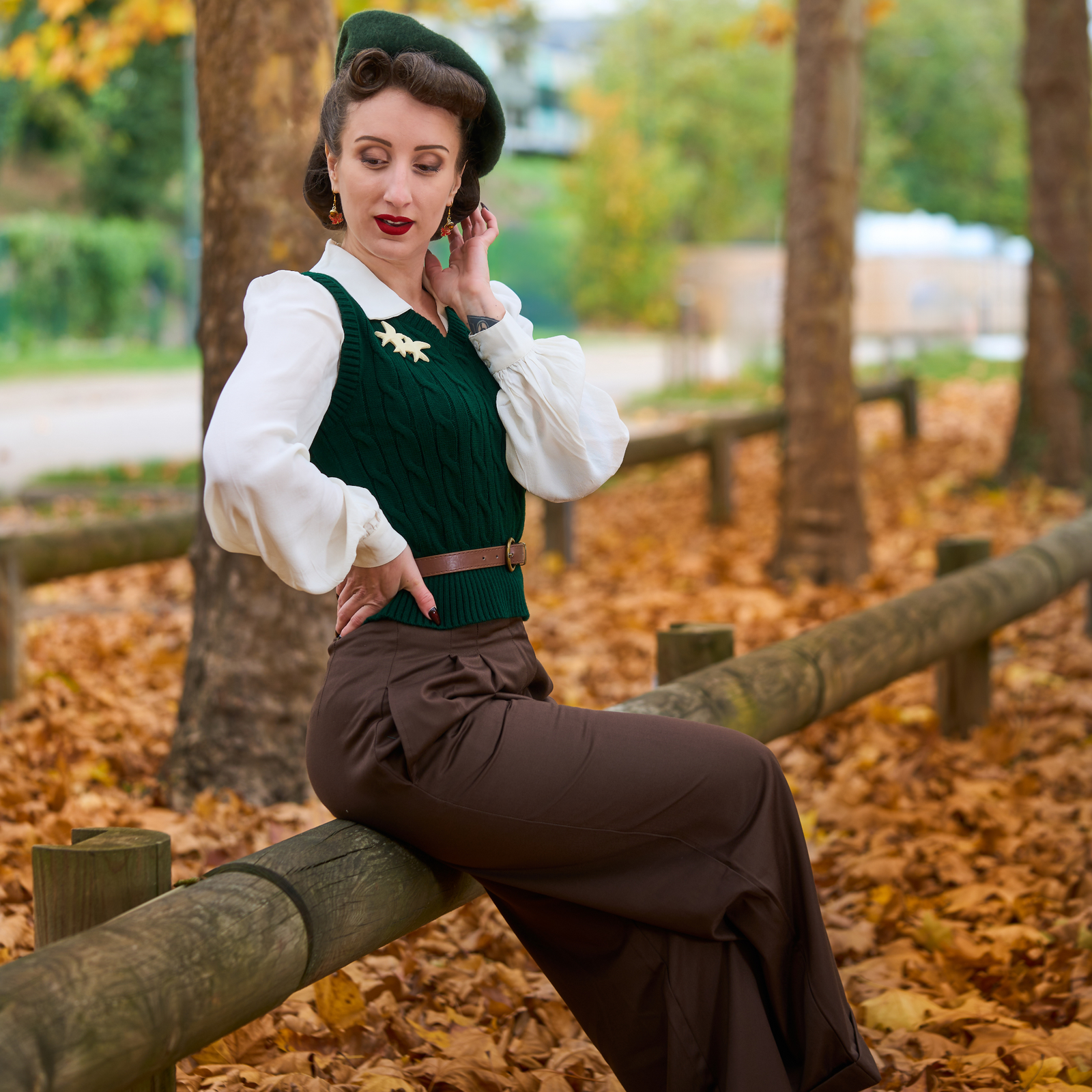 Woman in vintage attire sitting on a wooden fence in an autumn setting