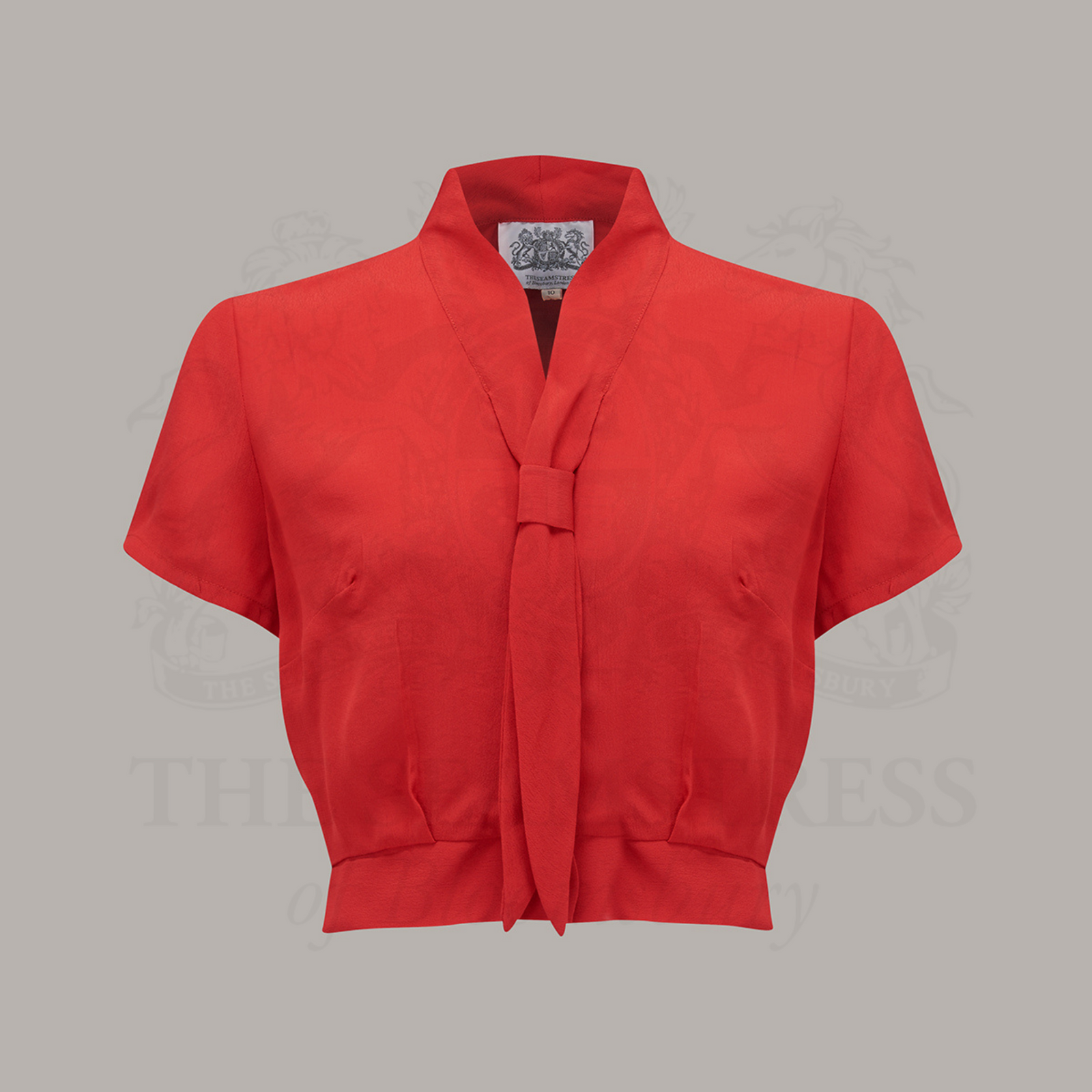A 1940s sailor-style blouse in red. Featuring a roll-style sailor collar. Small buttons run down the front of the blouse for fastening but are hidden by the long collar.
