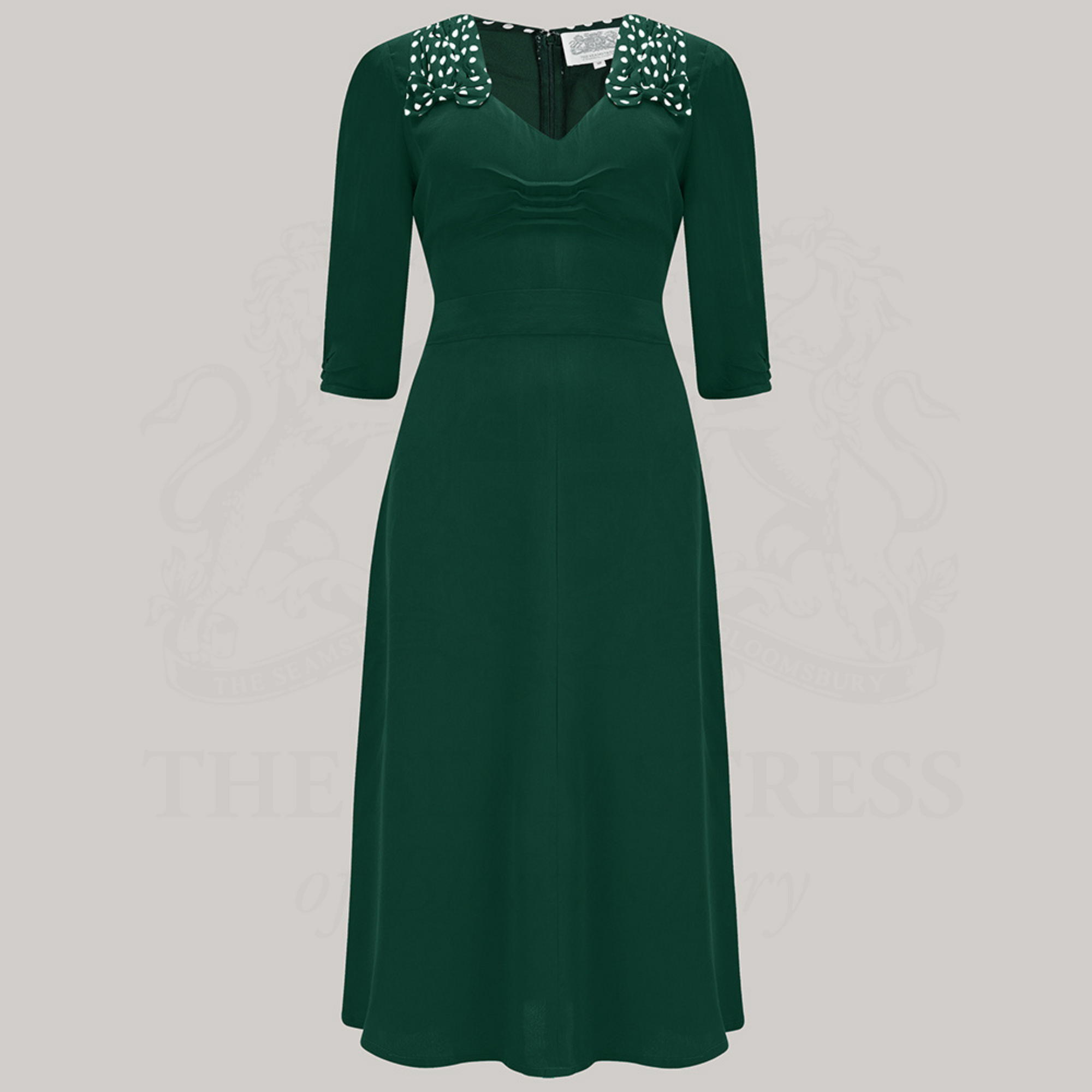 A green dress with polka dots on the shoulders, featured on a grey background.