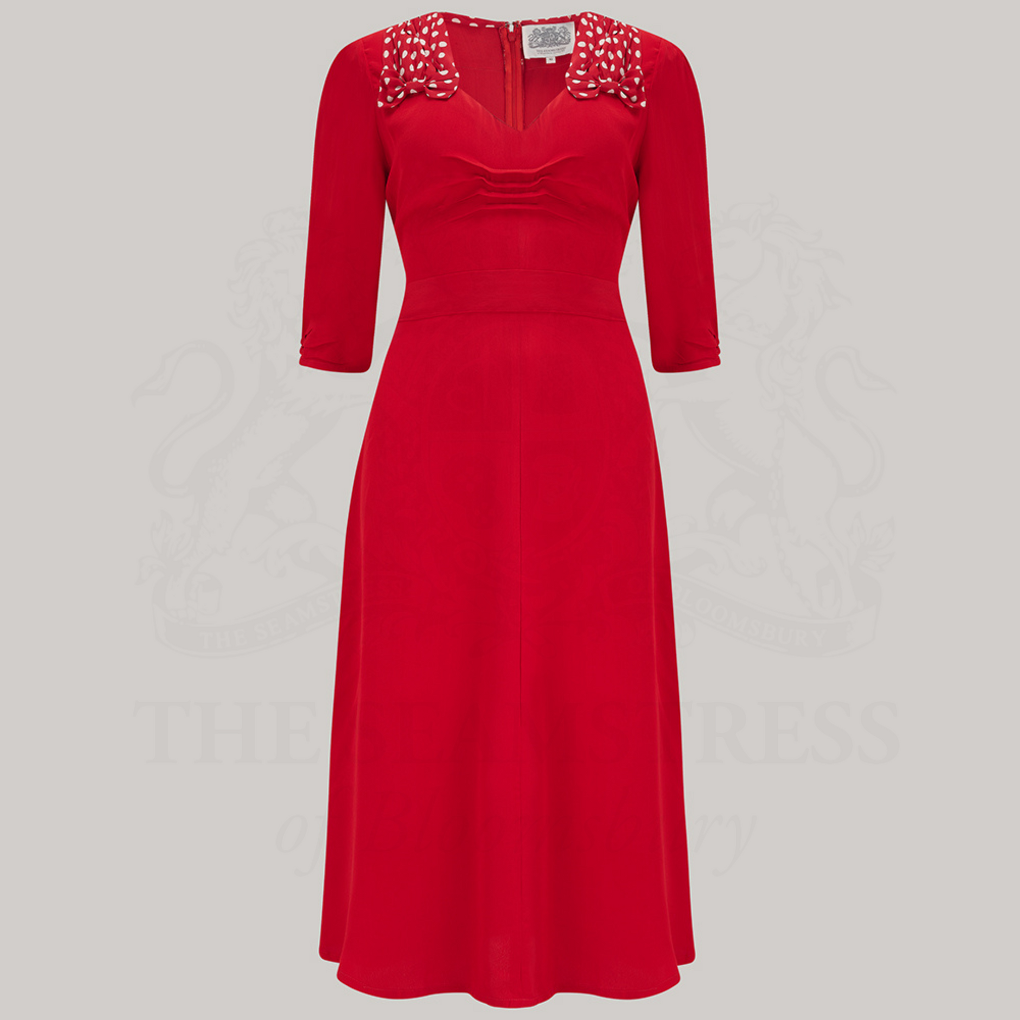 A red dress with polka dots on the shoulders, featured on a grey background.