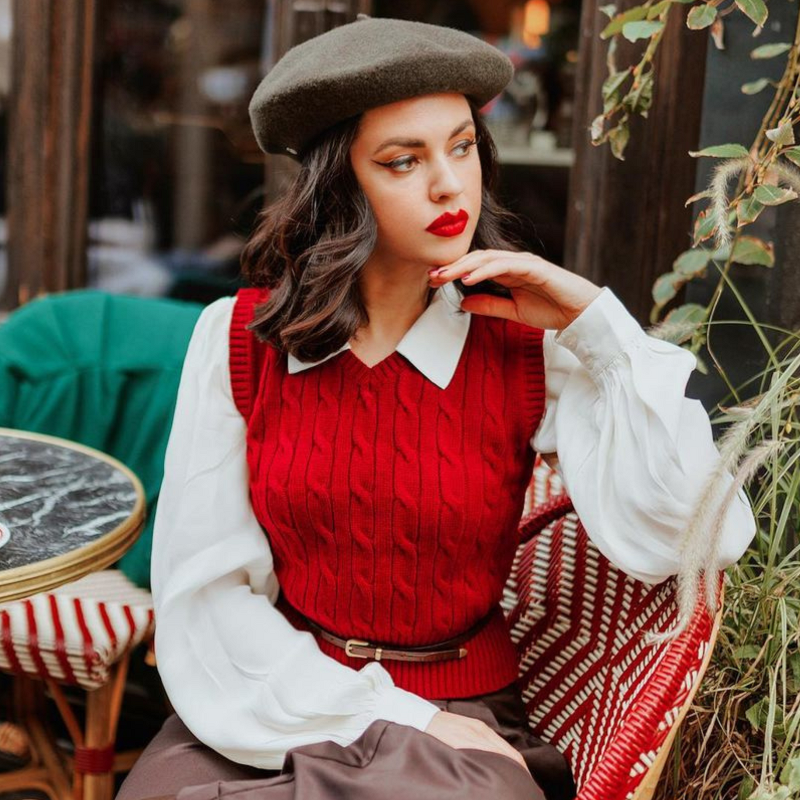 Model wears a burgundy 1940s-style knitted vest on top of a long sleeve cream blouse