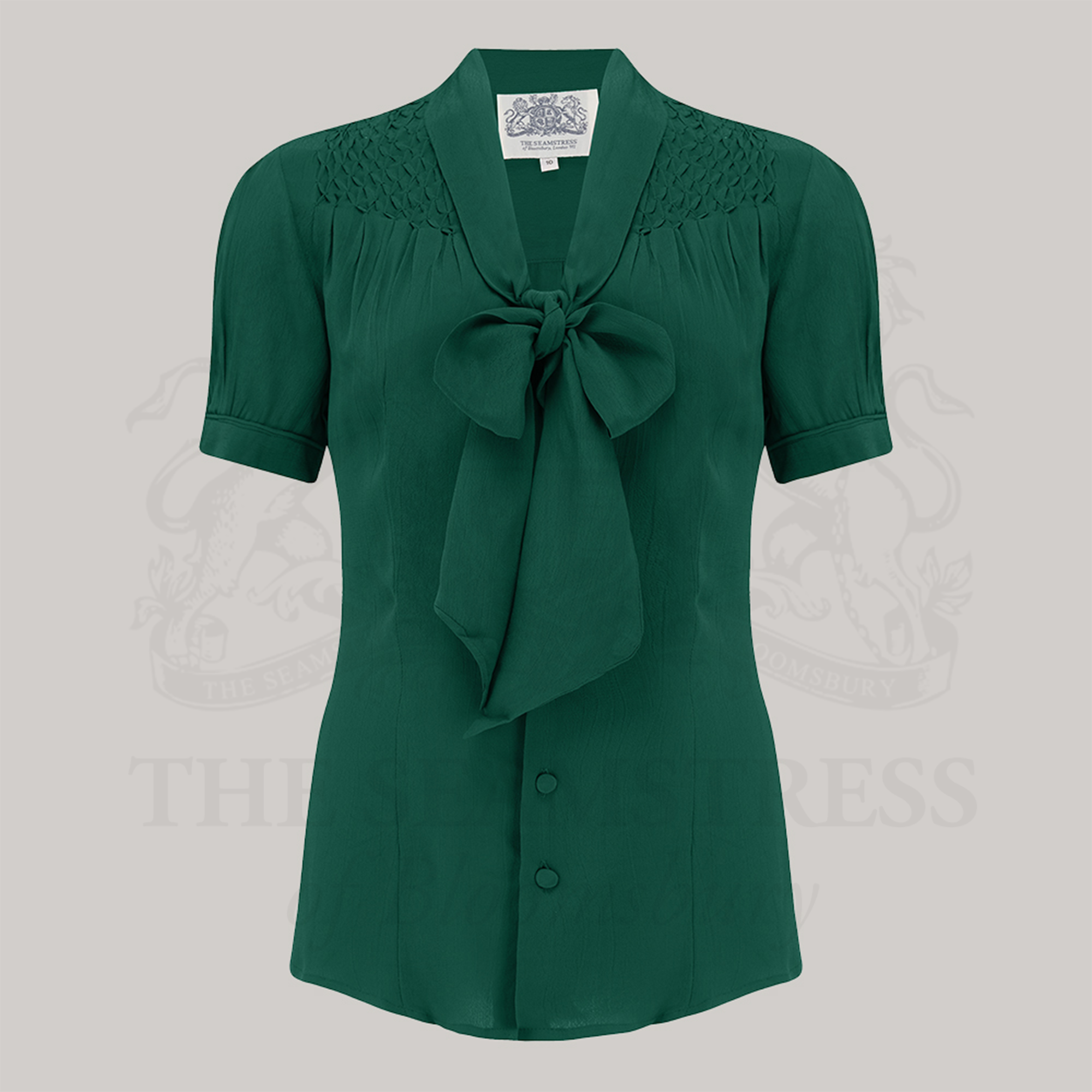 A green Eva pussy bow blouse with short sleeves and smock stitching on shoulders, 