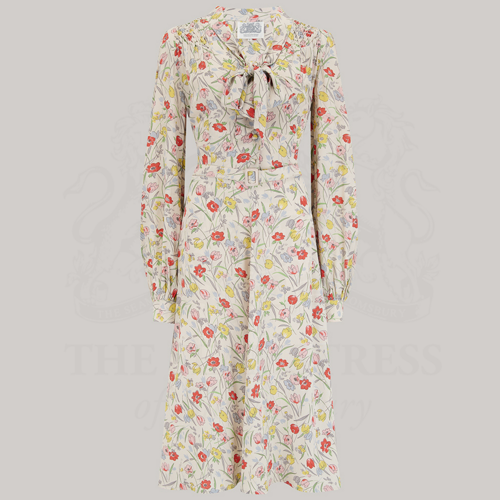 A vintage-inspired floral print dress with a pussy-bow neckline, long sleeves, and smock stitching on the shoulders.