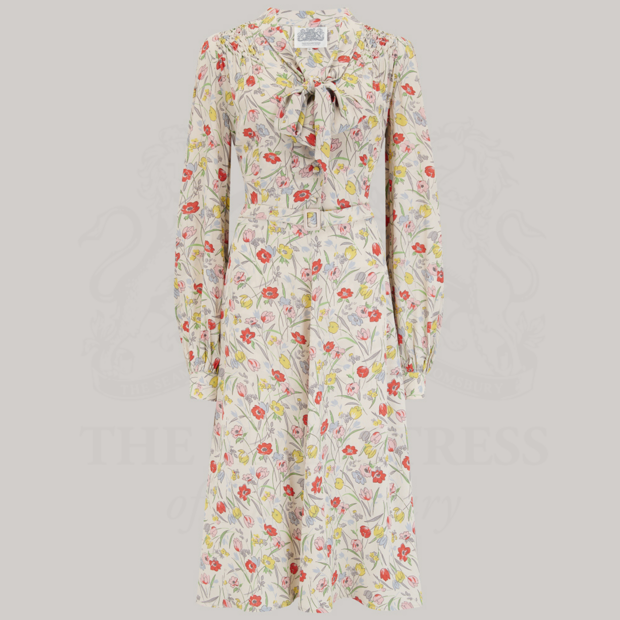 A vintage-inspired floral print dress with a pussy-bow neckline, long sleeves, and smock stitching on the shoulders.