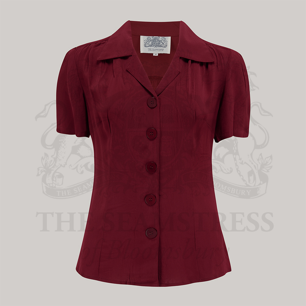 A red, short-sleeved blouse with a revere collar and large bakelite buttons.