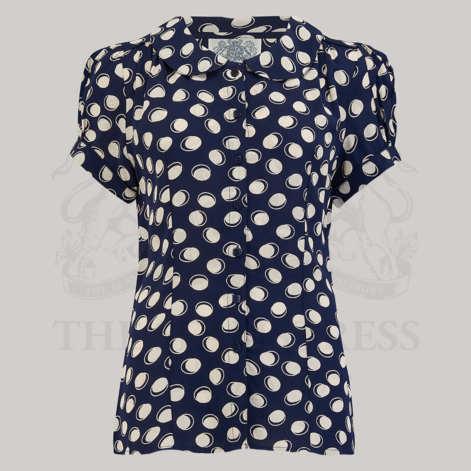 A navy blouse with a Peter Pan collar, short puff sleeves, and front button fastenings, displayed on a mannequin.