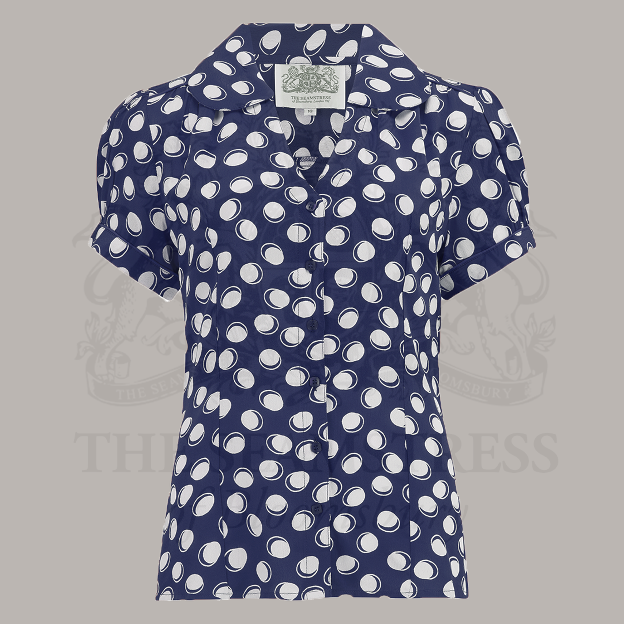 A navy blouse with white polka dots featuring a Peter Pan-style collar and puff sleeves.