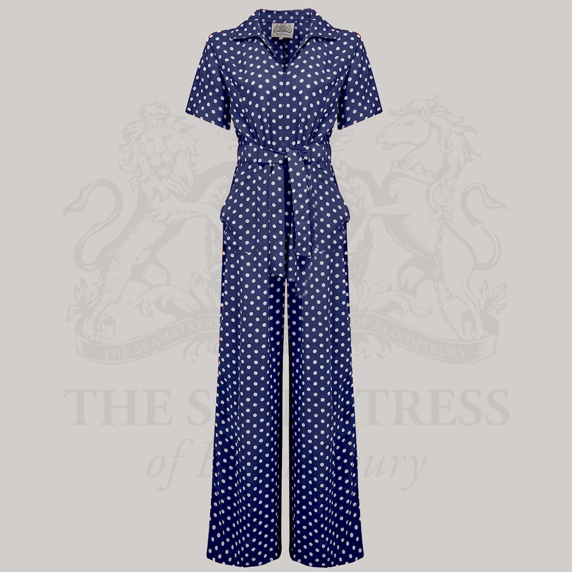 A navy siren suit with white polka dots featuring wide-leg trousers, short turn-back sleeves, and a front tie belt.
