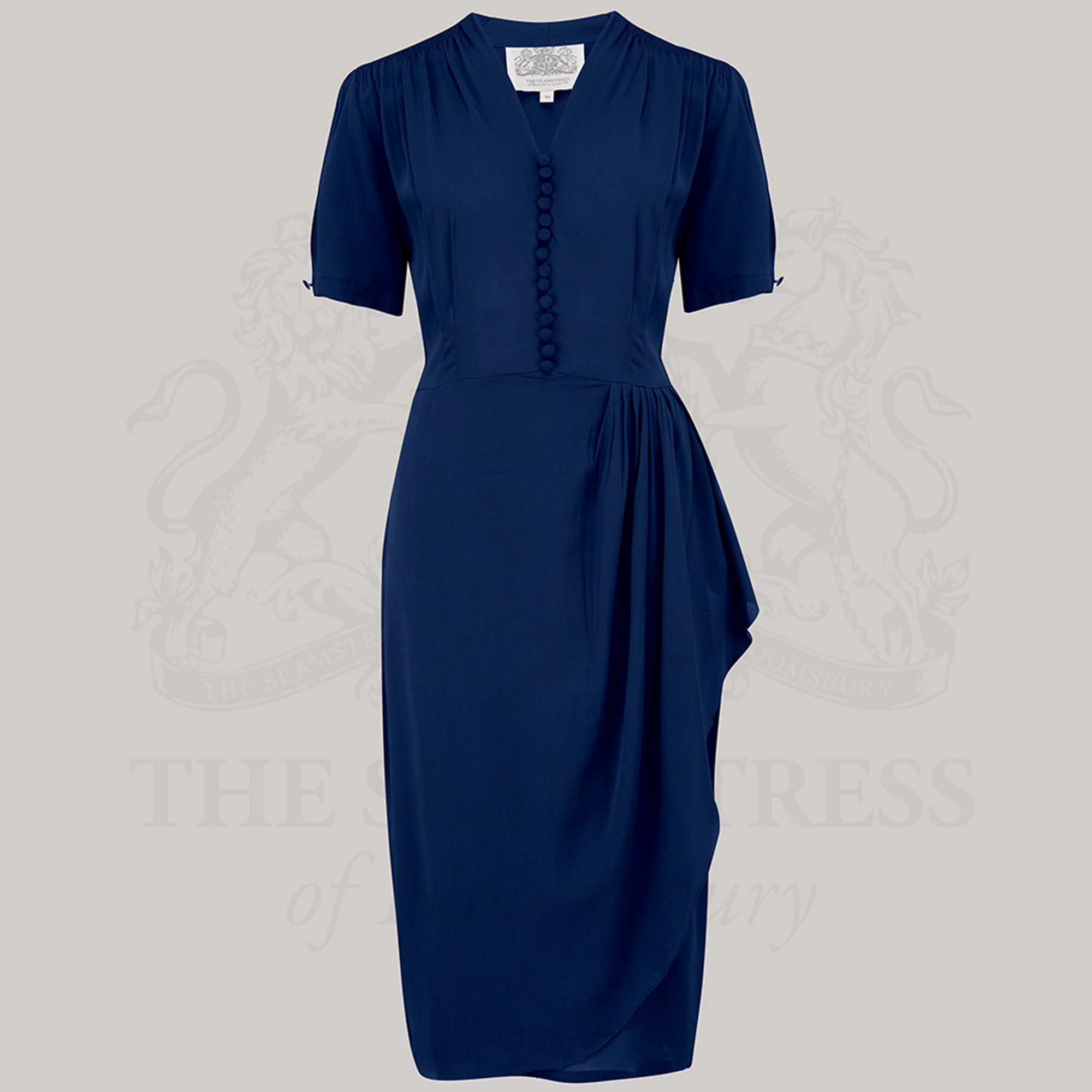 A navy blue dress with a fitted style, featuring a waterfall ruffle on the waist, decorative buttons on the front bodice, top shoulder smocking, side zip closure, and side seam pockets.