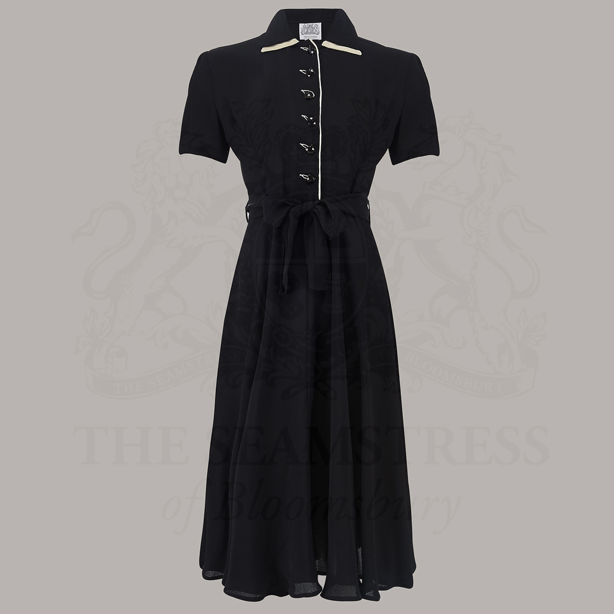 A classic 1940s black tea dress with square jet-style buttons and a cream undercollar. 