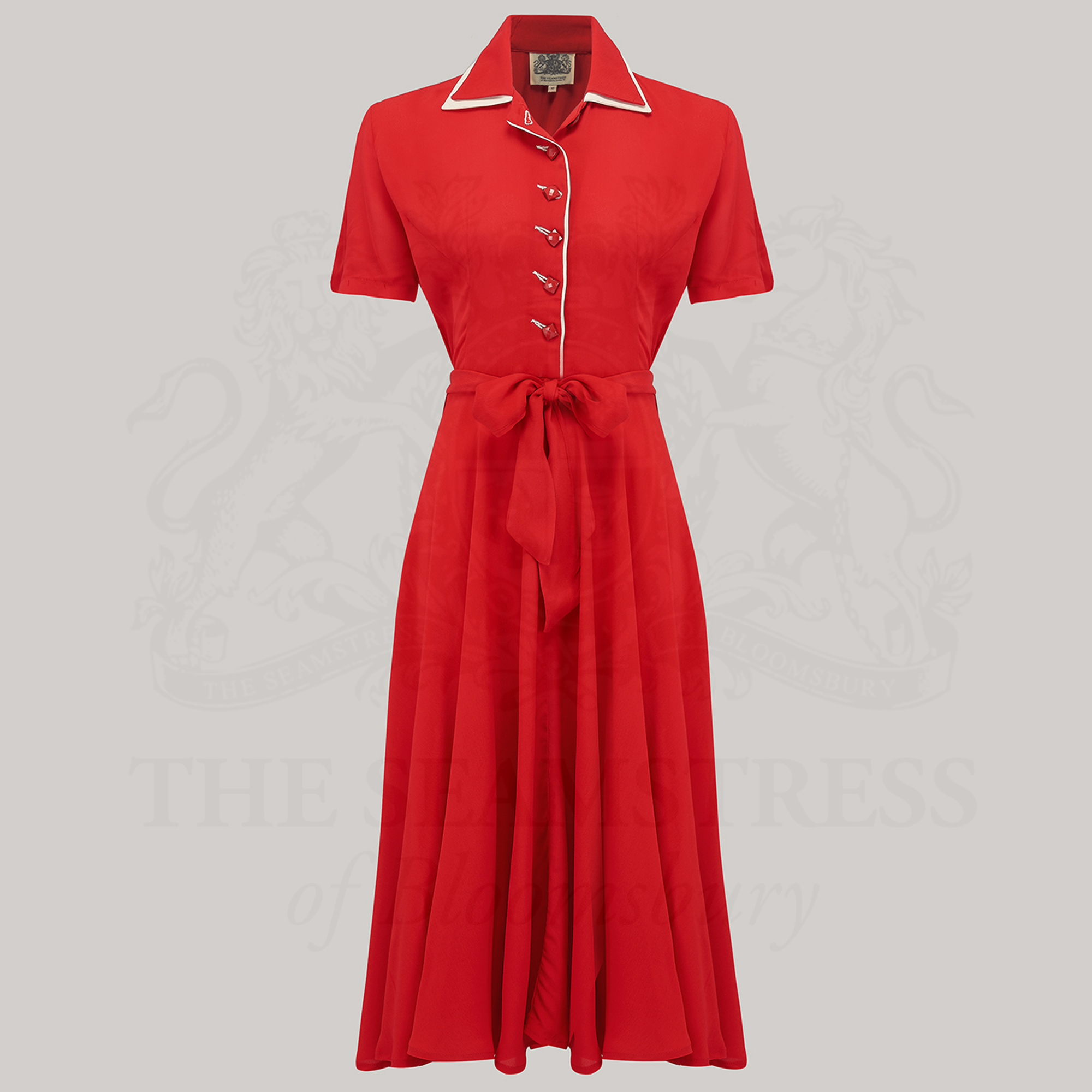A red 1940s-style tea dress with square jet-style buttons and a cream undercollar.
