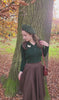 Model wears a 1940s-style cable knitted cardigan in dark green with a matching beret and brown skirt. 