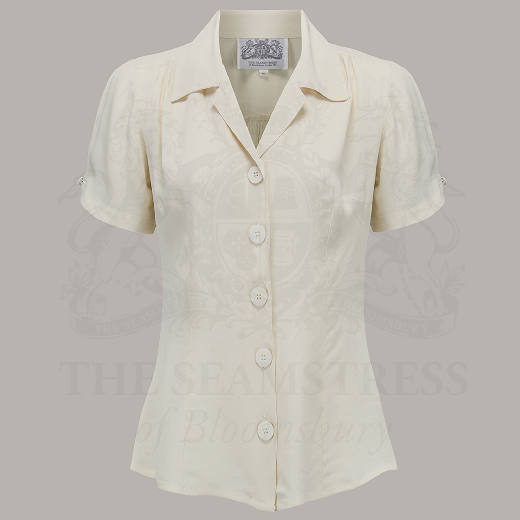 A  cream-colored blouse with a revere collar, large bakelite buttons, and short sleeves