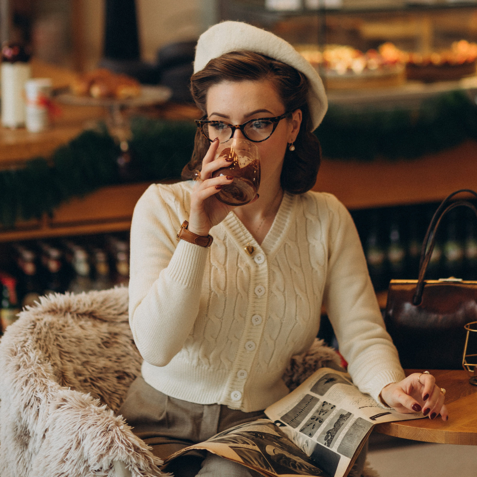 Model wears a 1940s style cable knitted cardigan in cream, curled vintage style hair with a matching cream beret. Matching cream buttons feature down the front of the cardigan.