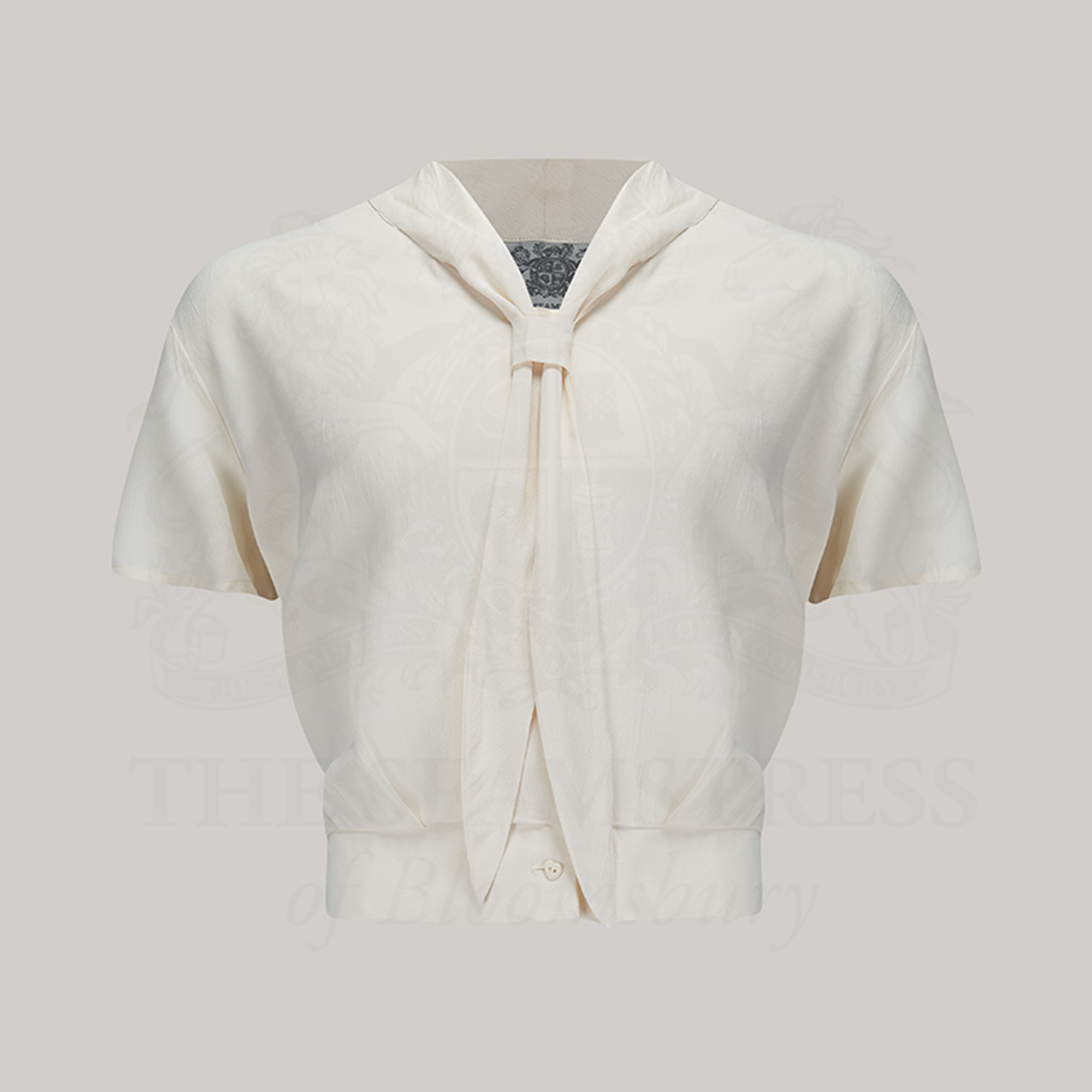 A 1940s sailor-style blouse in cream. Featuring a roll-style sailor collar. Small buttons run down the front of the blouse for fastening but are hidden by the long collar.
