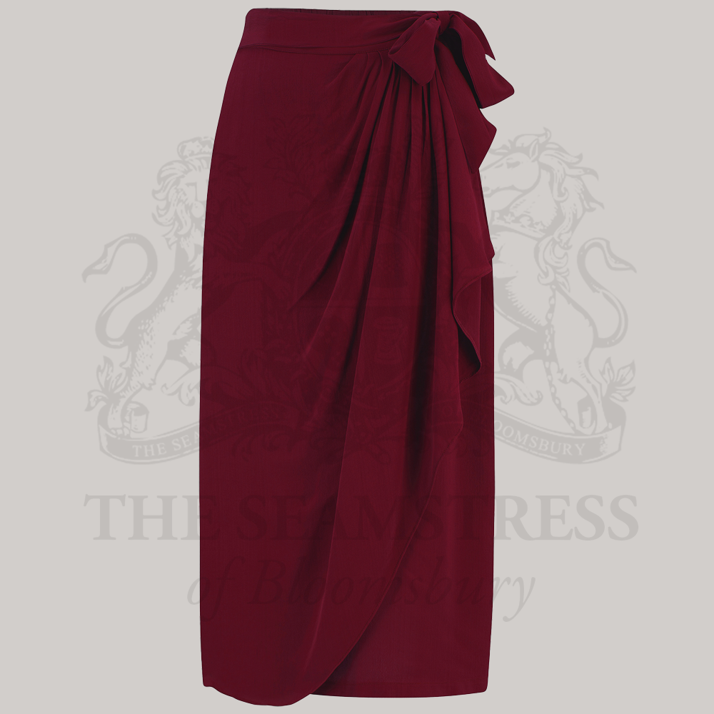 A burgundy 1940s-inspired skirt featuring a waterfall ruffle on one side, and an elasticated waistband
