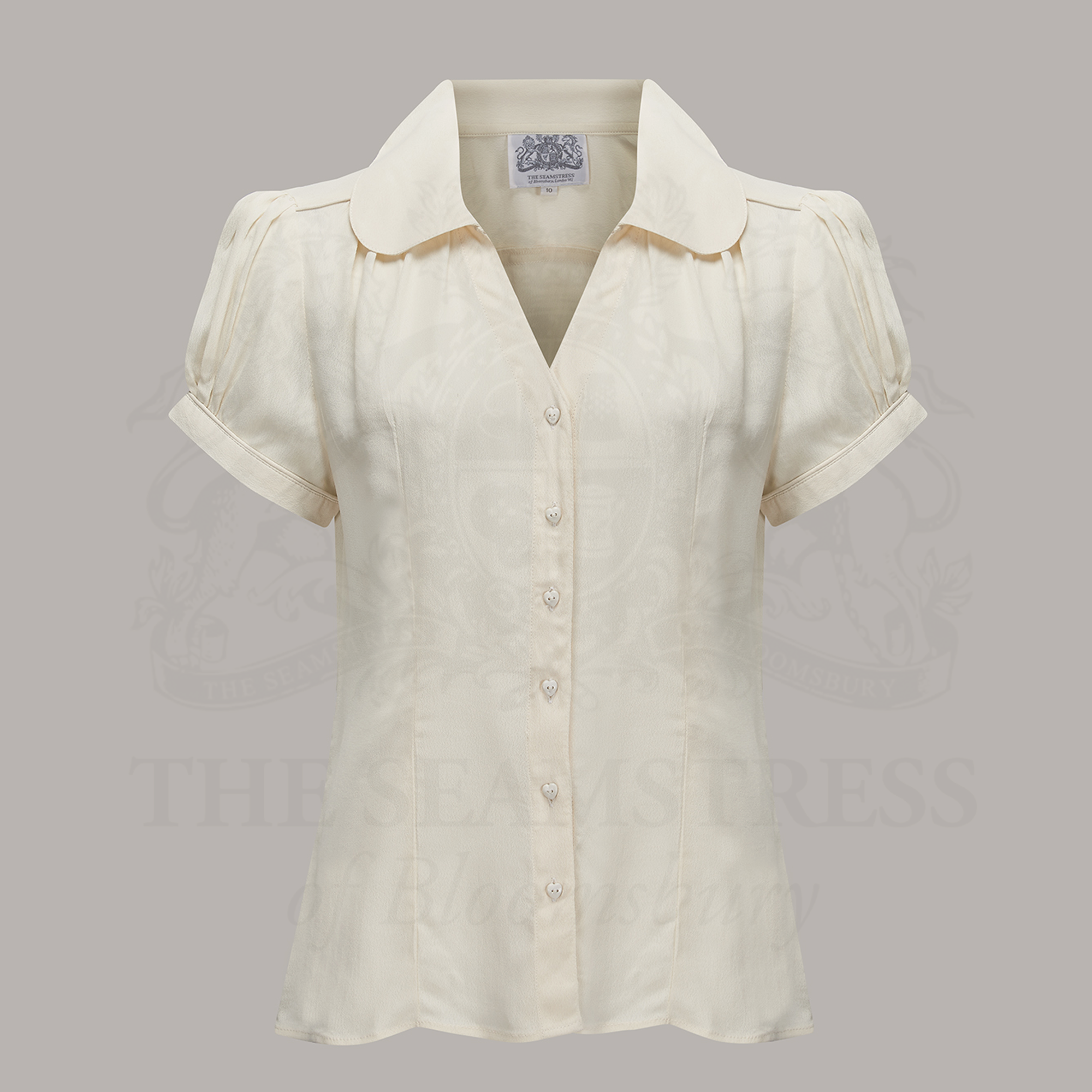 A  vintage-style cream blouse with a Peter Pan-style collar, puff sleeves, and a fitted waist