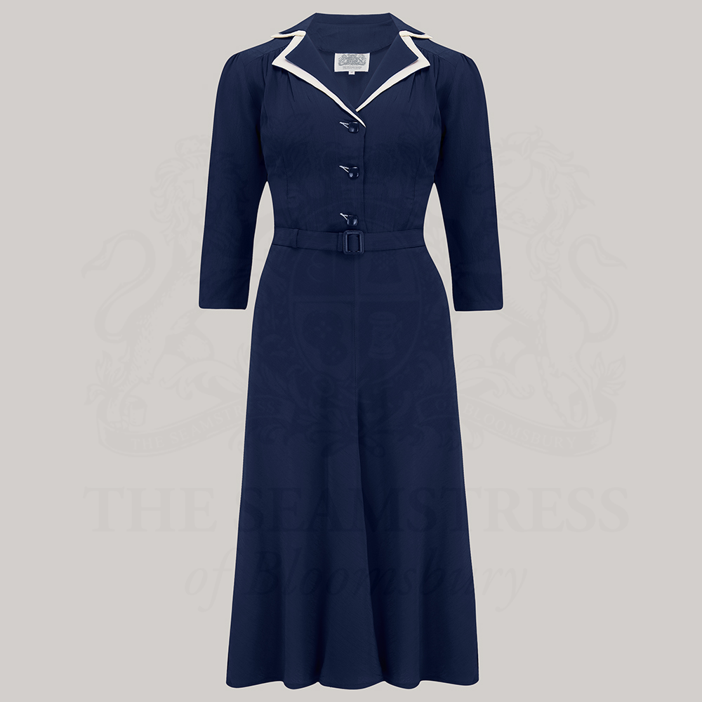 A navy dress with a contrasting cream undercollar, square jet-style buttons, and a side zip closure. 